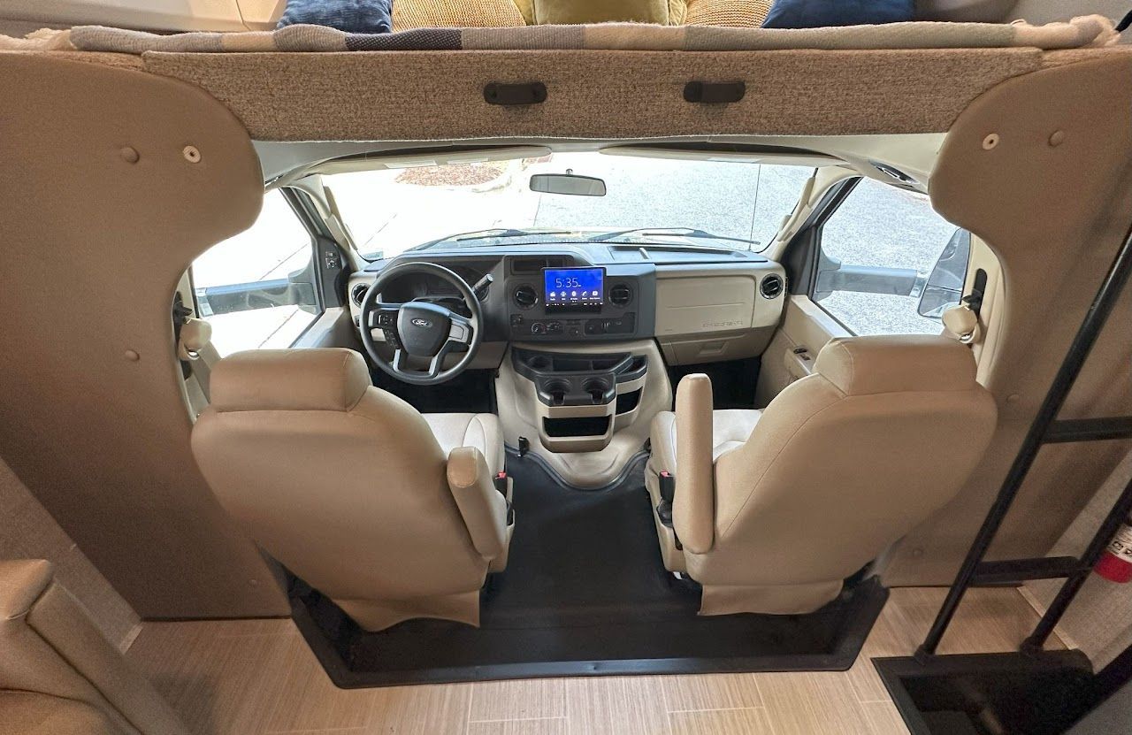 The inside of a rv with two seats and a ladder.