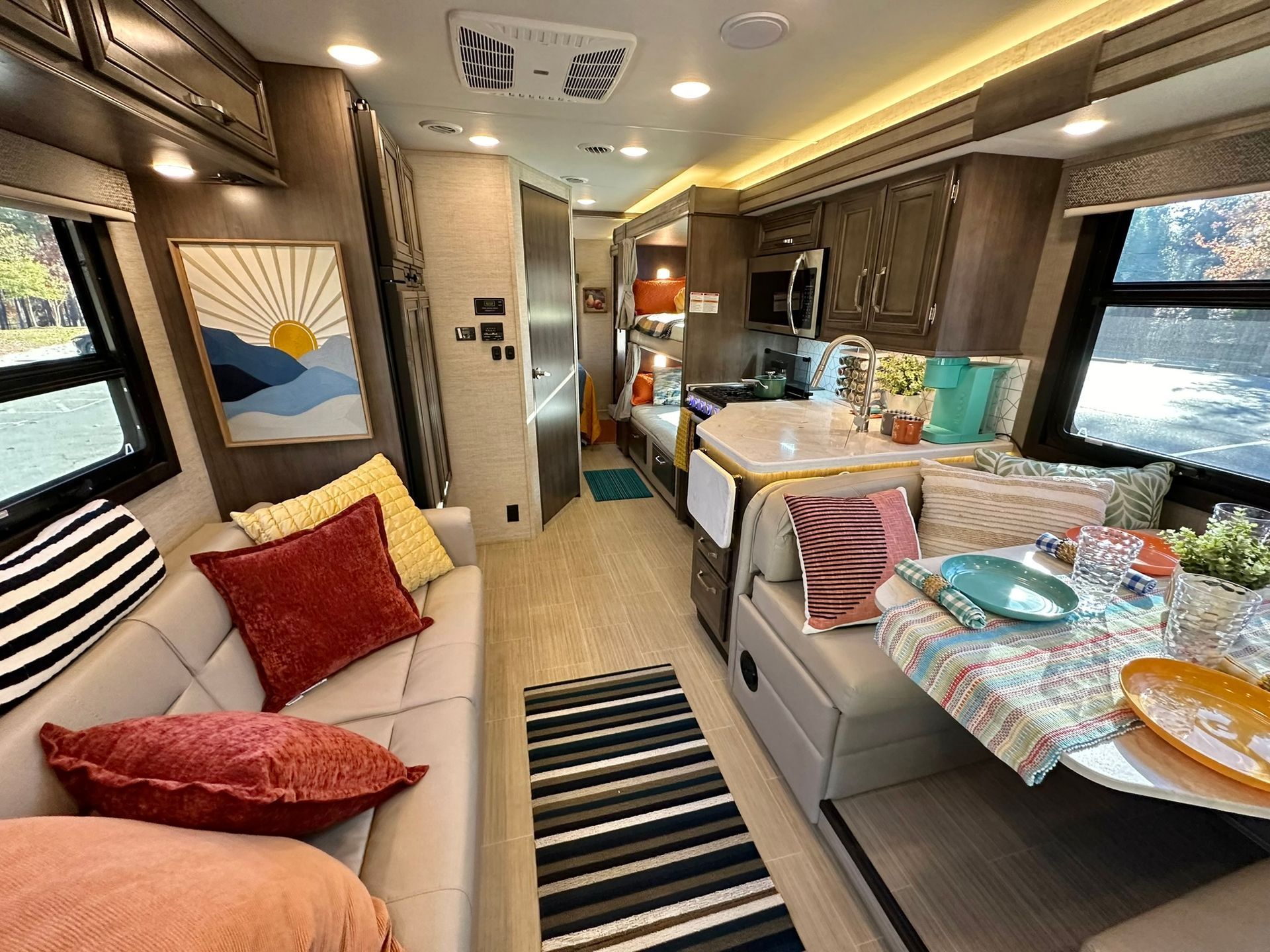 The inside of a rv with a couch , table , and rug.