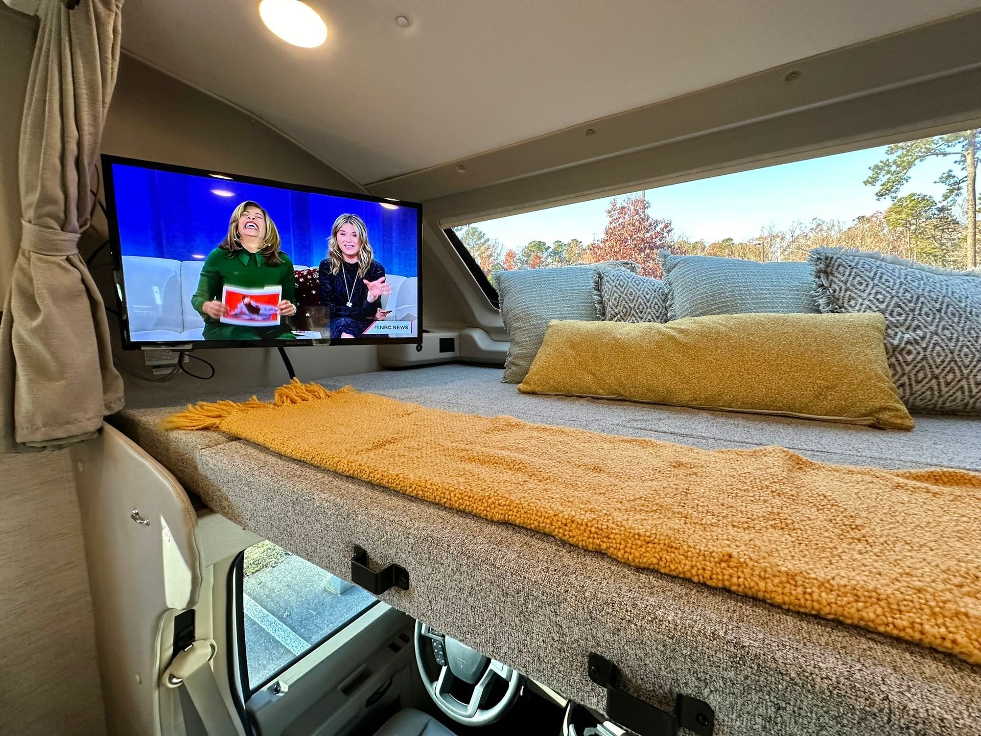 A bed with a television on top of it in a camper.