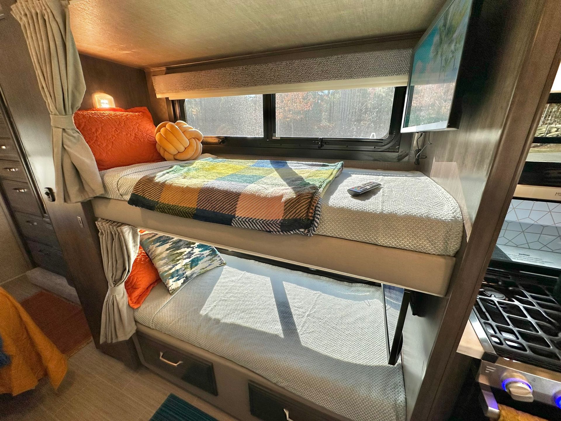 A rv with three bunk beds and a stove.