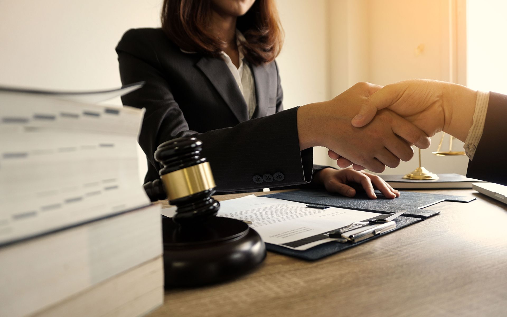 A woman is shaking hands with a man while sitting at a table.
