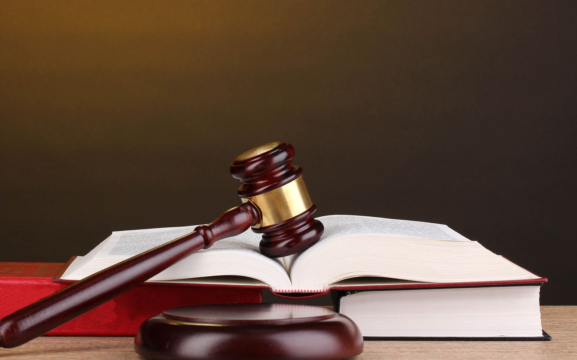 A wooden judge 's gavel is sitting on top of an open book.