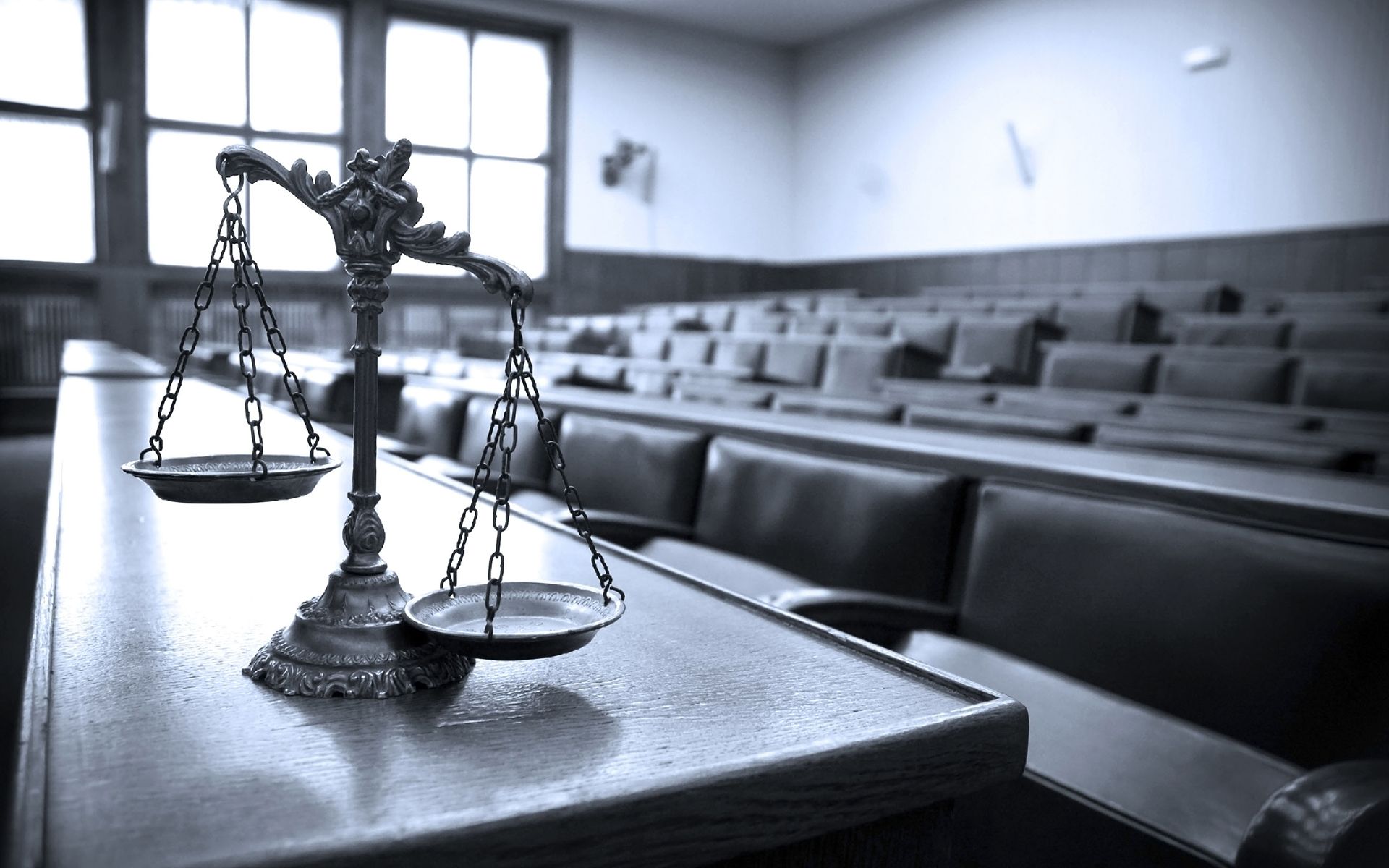 A scale of justice is sitting on a table in a courtroom.