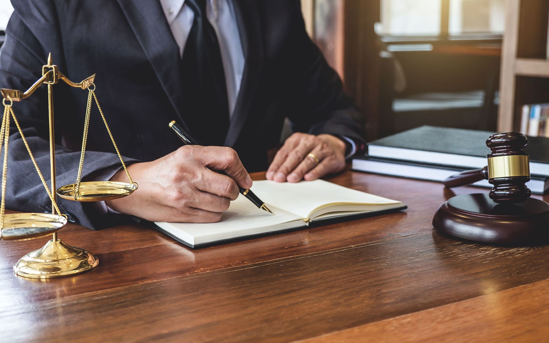 A lawyer is sitting at a desk writing in a notebook.