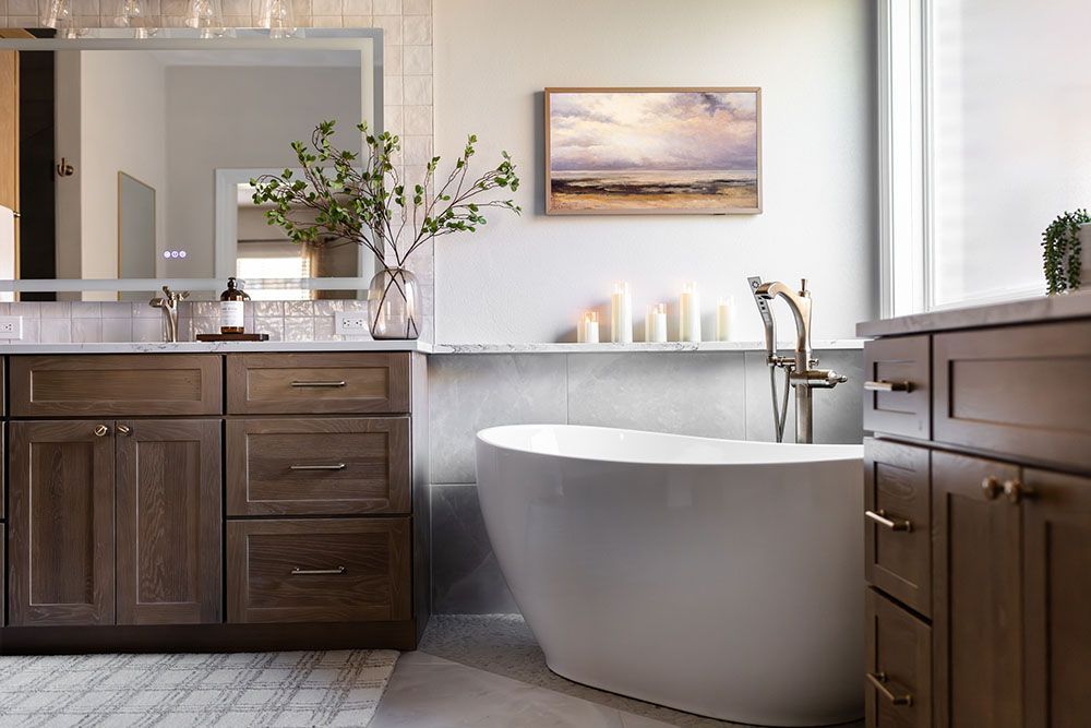 A modern bathroom featuring a white soaking tub, dark wood cabinets, a large mirror, and a wall painting of a seascape.