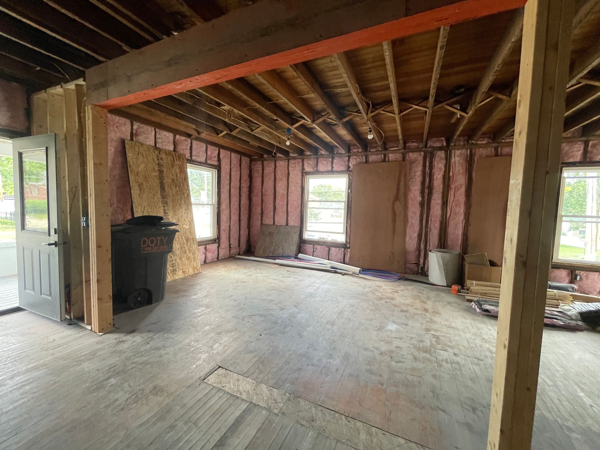 Unfinished room with exposed studs, open windows, and a bare subfloor under construction