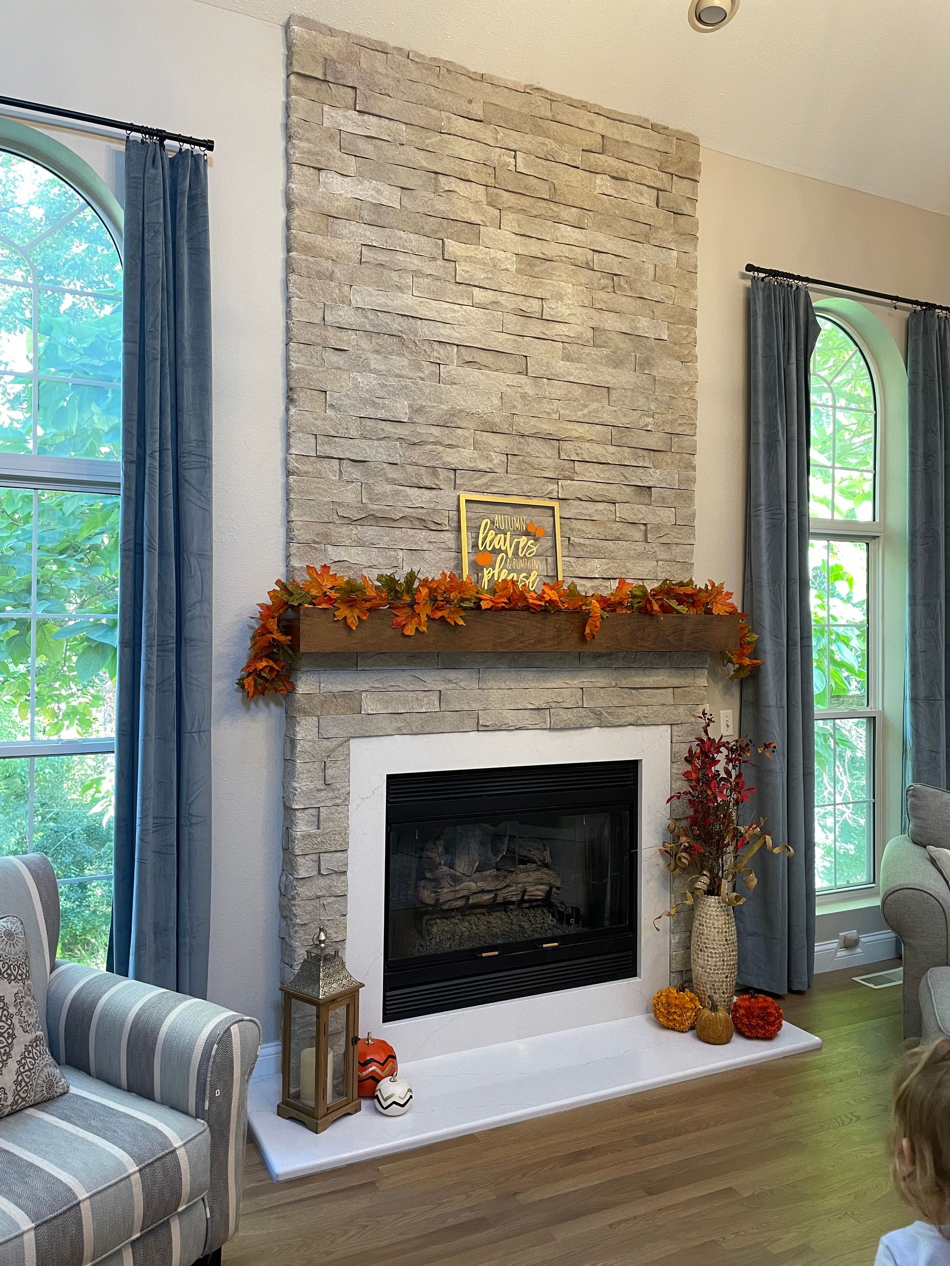 Living room fireplace with fall garland, brick surround, and tall arched windows