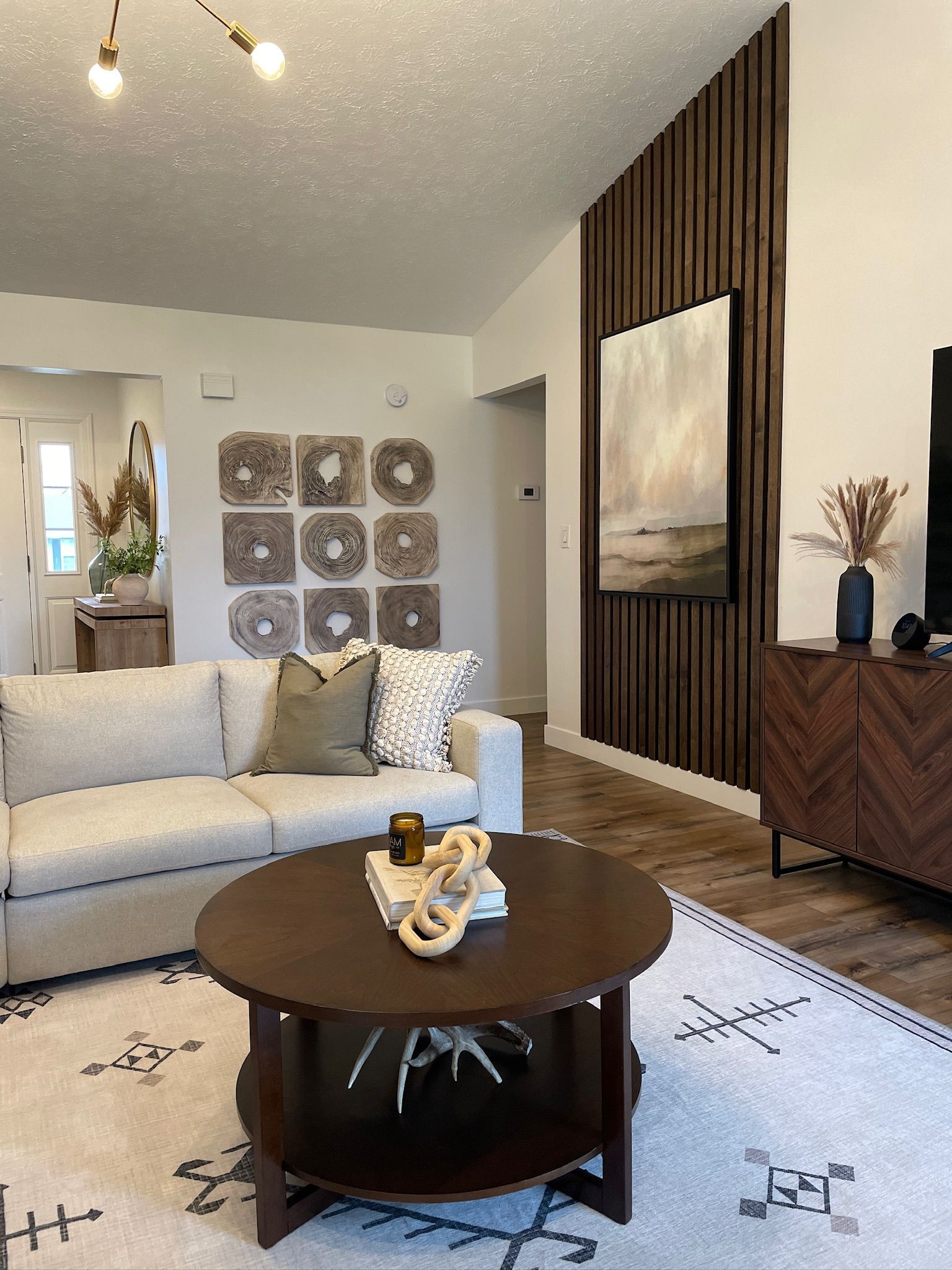 Living room with wood accent wall, art, sofa, rug, and coffee table