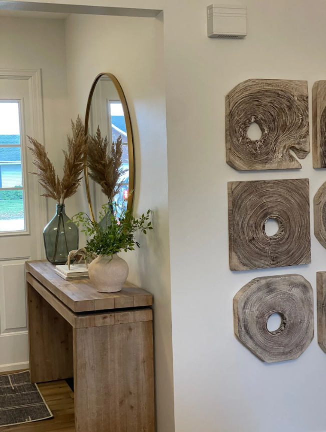 Entryway with a wooden console table, mirror, vases of pampas grass and greenery, and wall art.