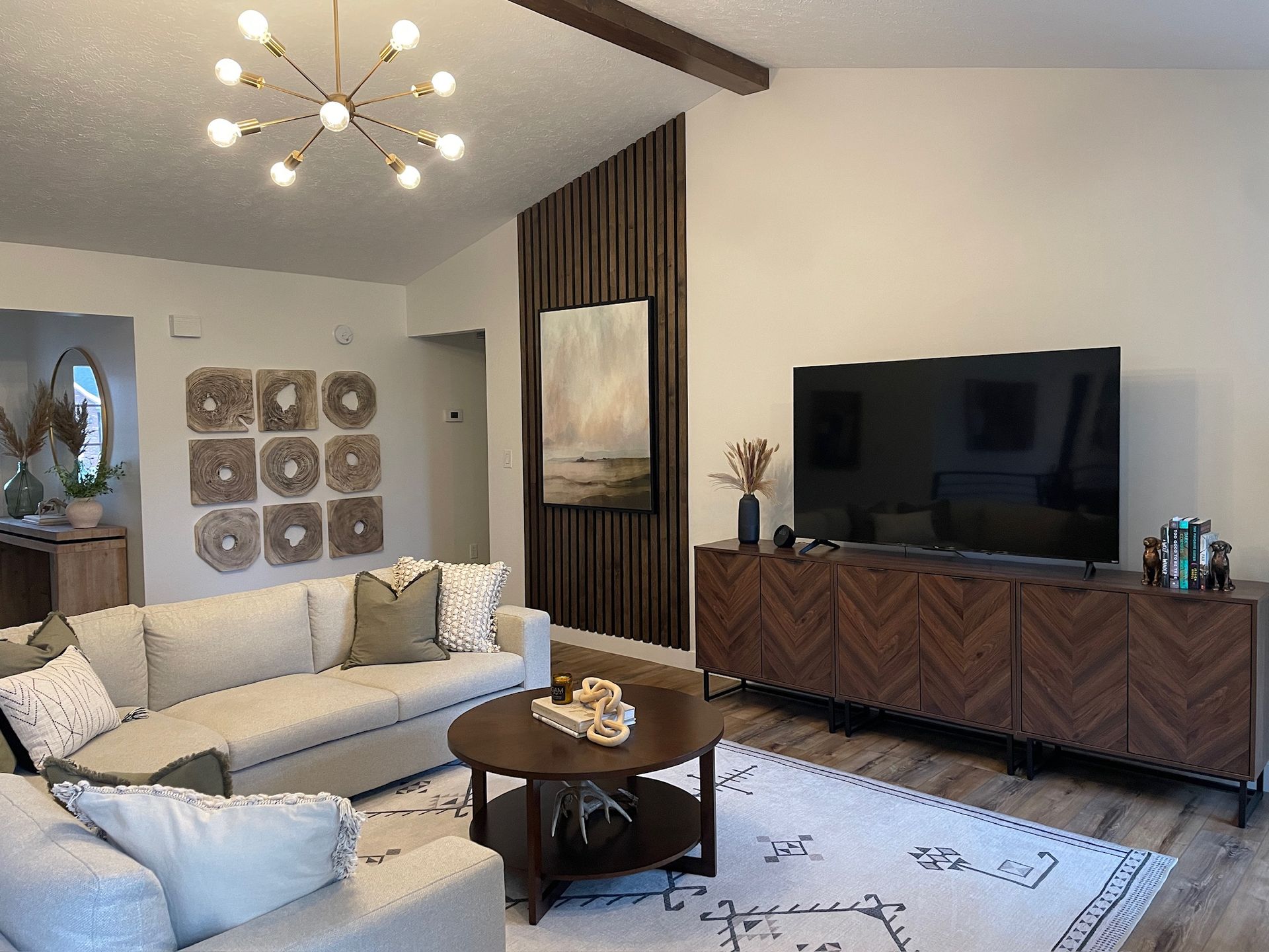 Cozy living room with fireplace, sectional sofa, and open-concept kitchen. Neutral colors, modern decor.