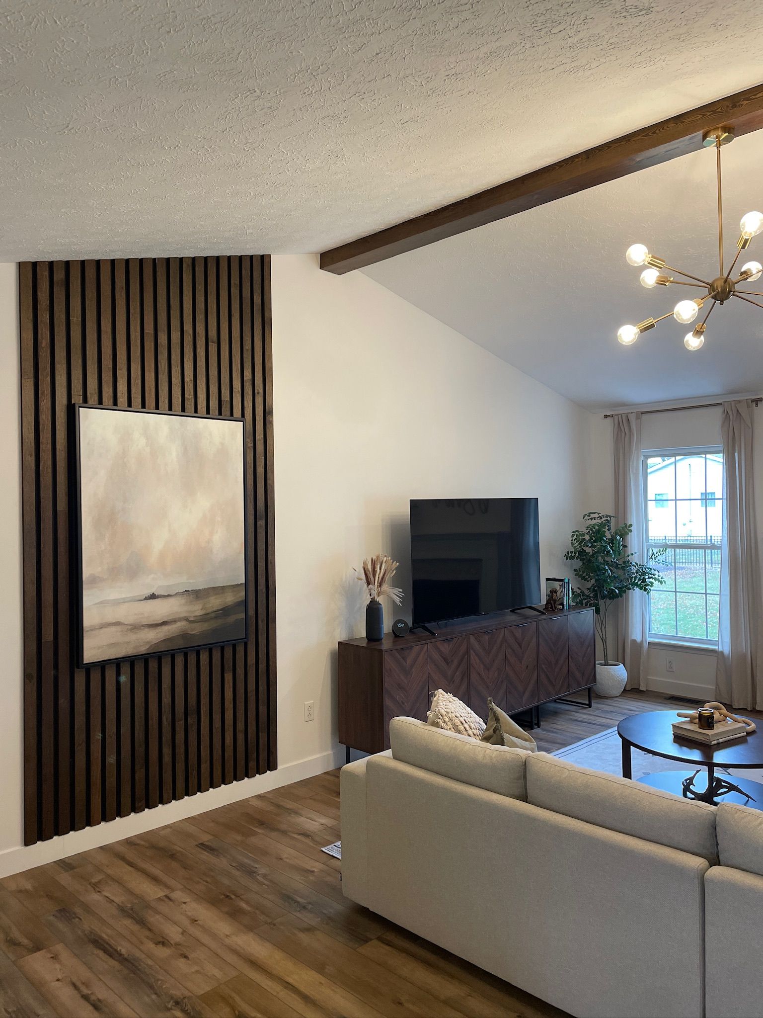Living room with wooden panel wall, artwork, and modern furniture.