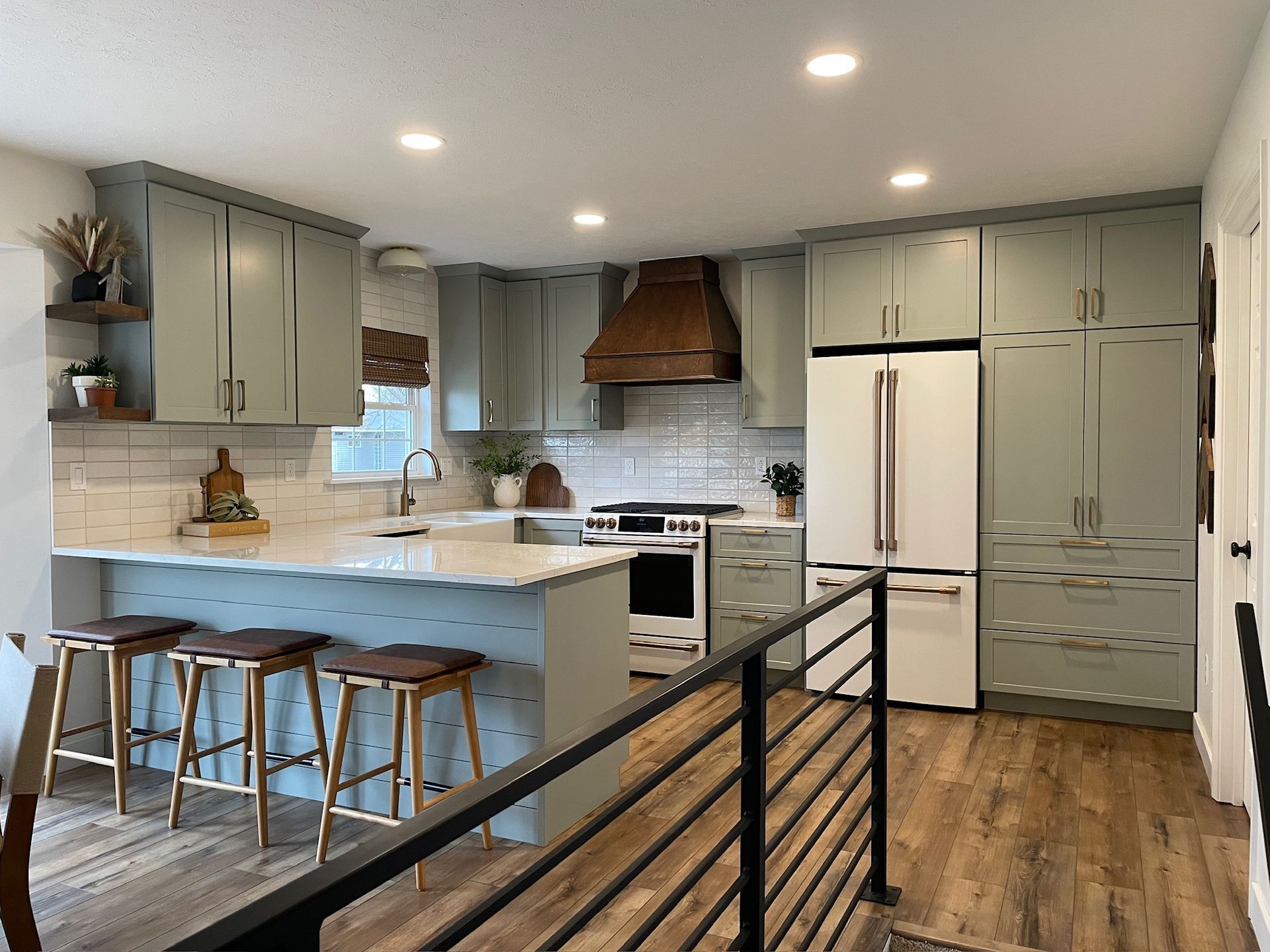 Kitchen with sage green cabinets, white appliances, and a wood range hood.