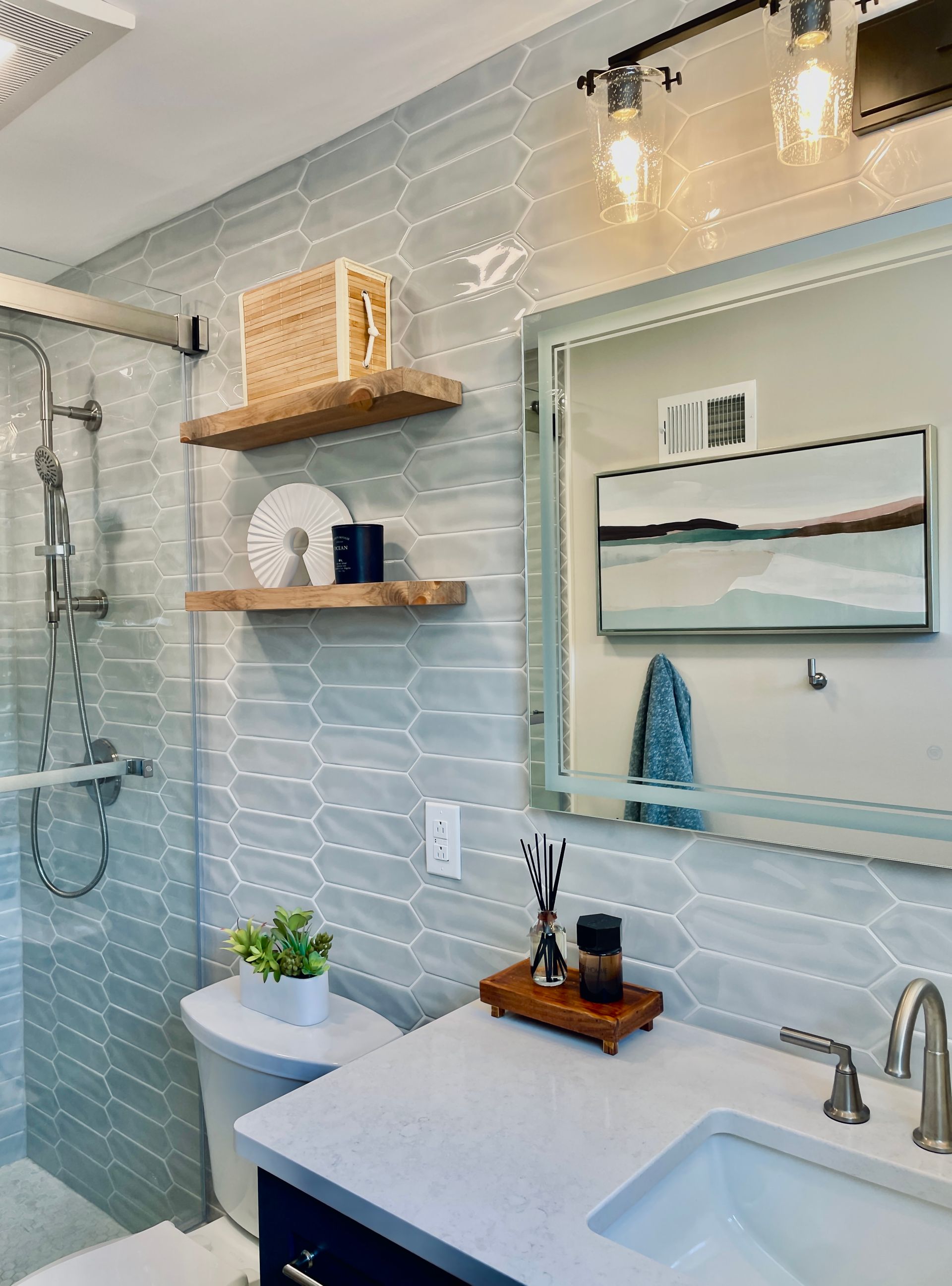 Bathroom with blue and white patterned tile, floating shelves, and a vanity with a large mirror.