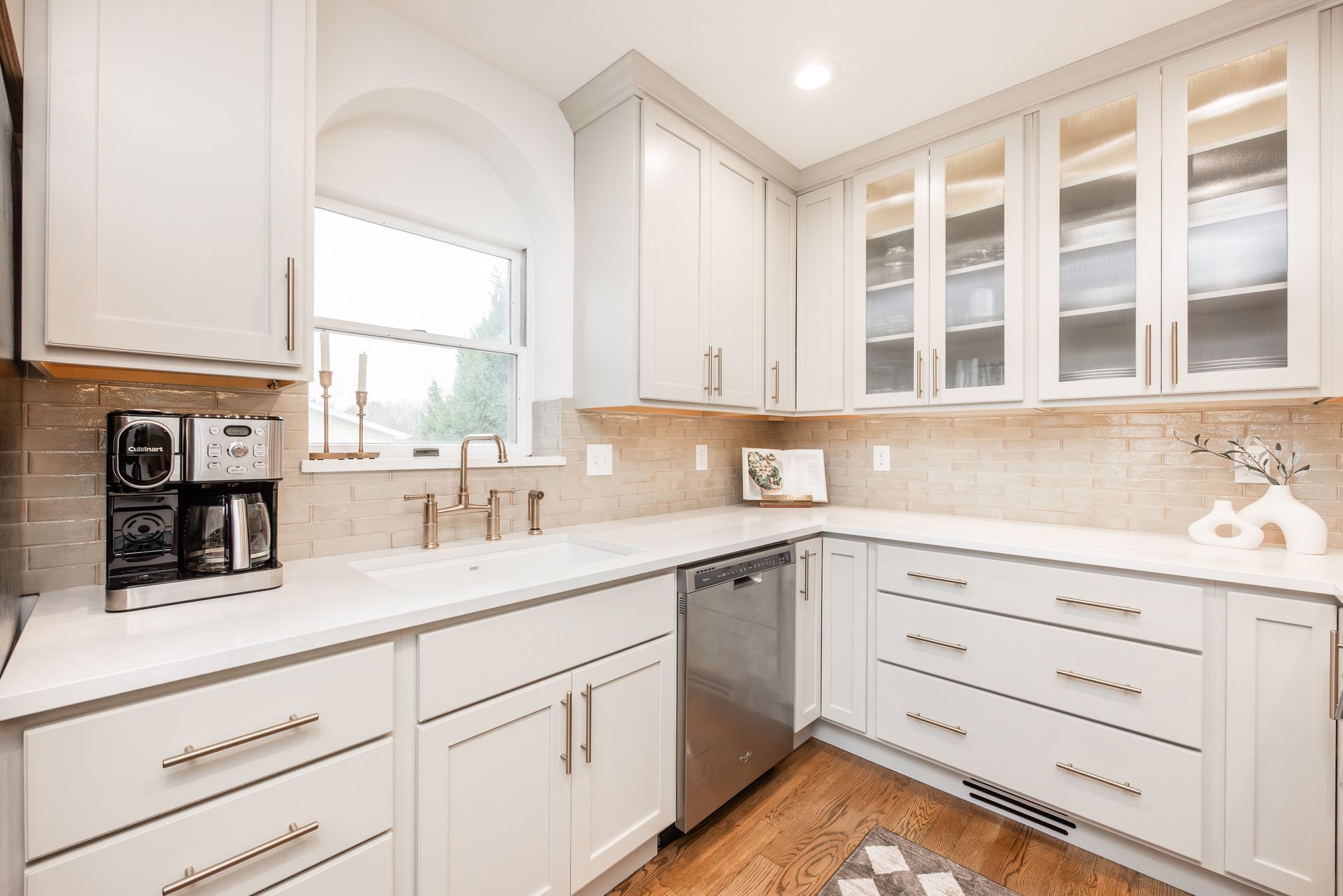 A well-lit, modern kitchen with light gray cabinets, white countertops, and stainless steel appliances.