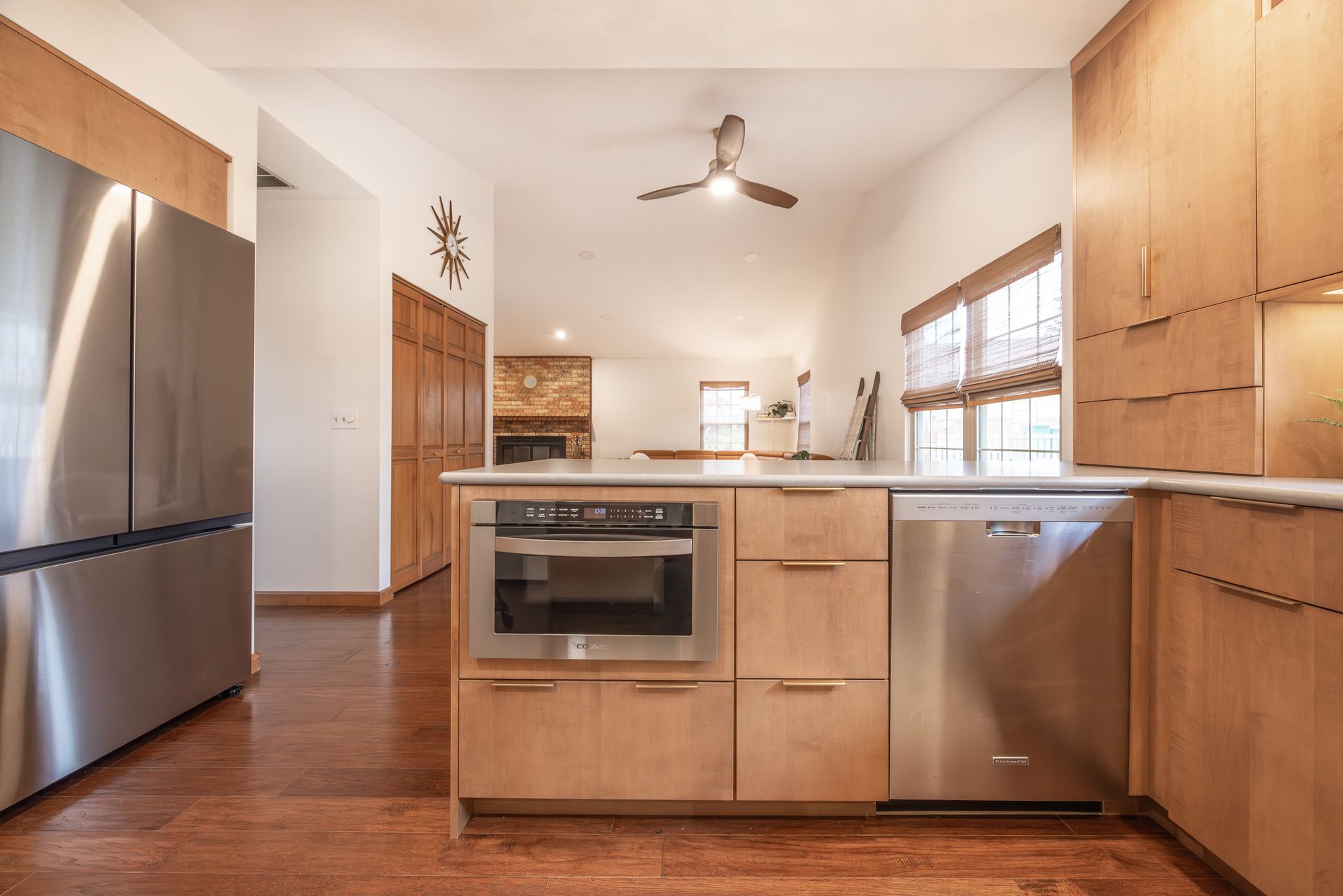 Modern kitchen with stainless steel appliances, light wood cabinets, and an island.