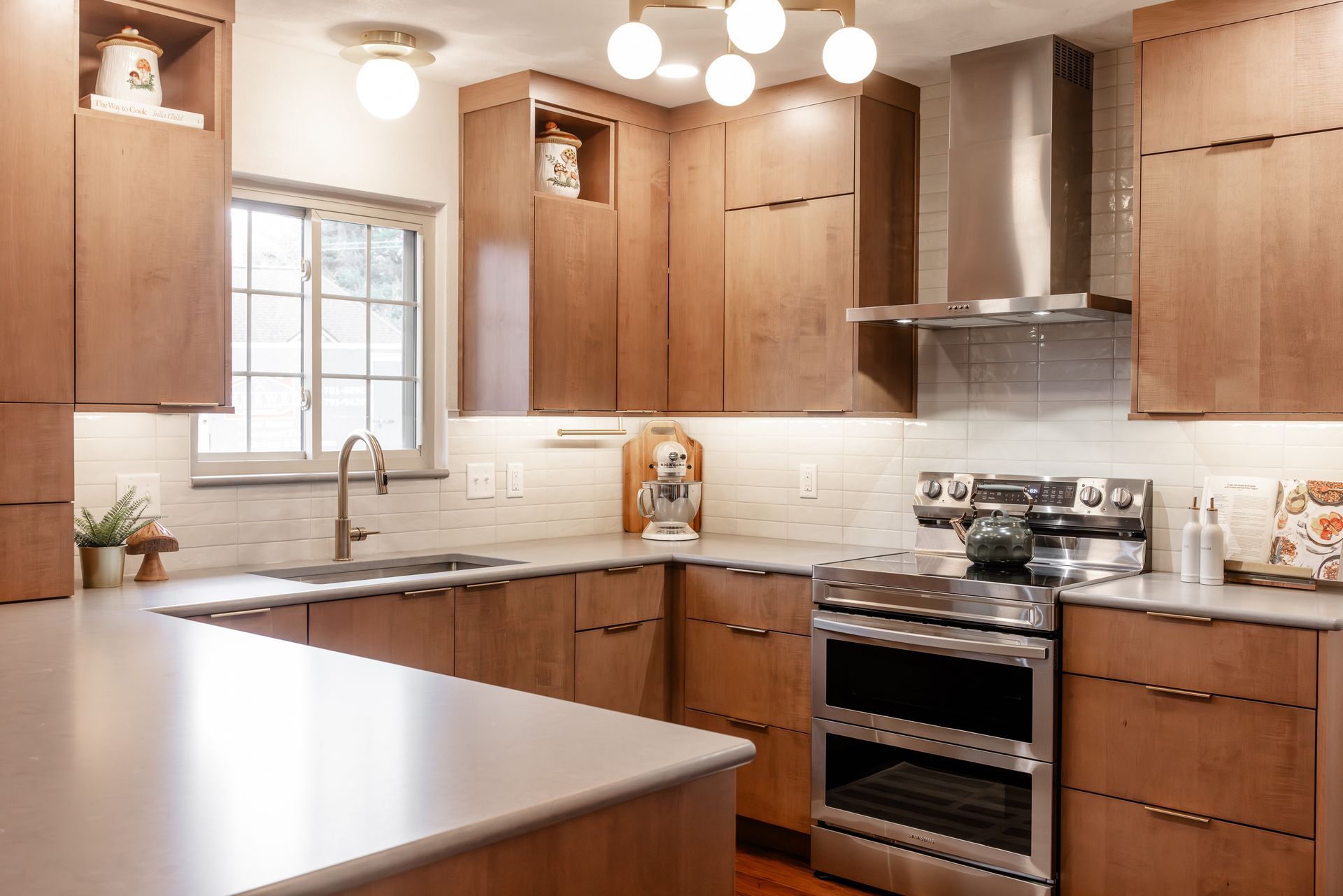 A modern kitchen with light wood cabinets, stainless steel appliances, and a light countertop.