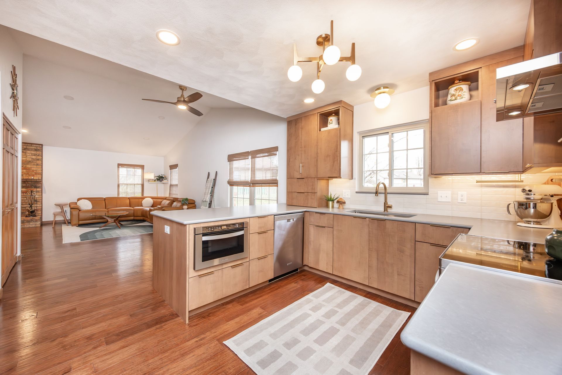 Modern kitchen with wood cabinets, island, and open view to living room.