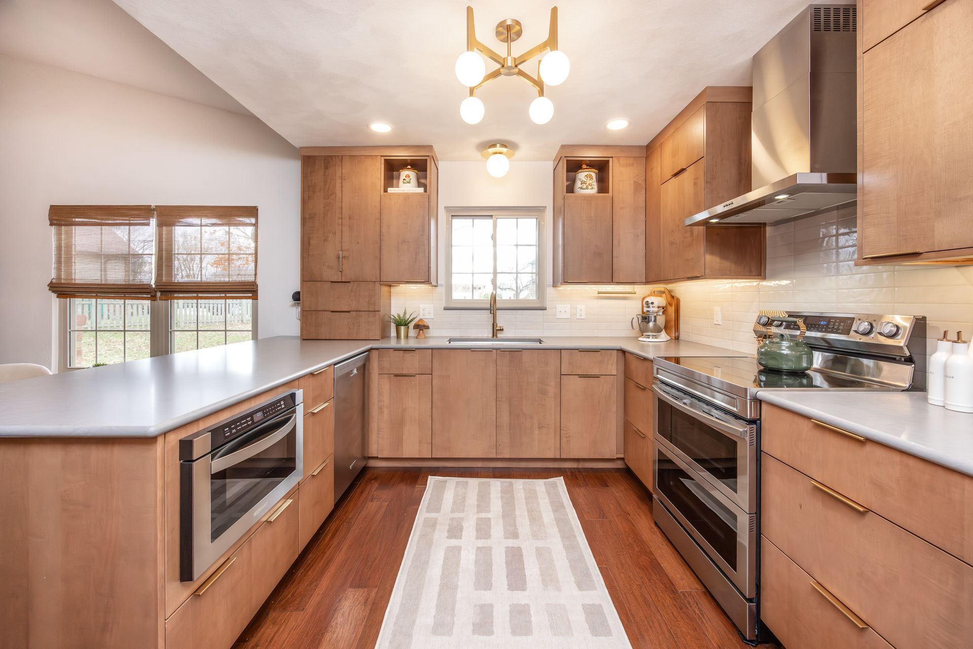 Modern kitchen with light wood cabinets, stainless steel appliances, and a gray countertop.