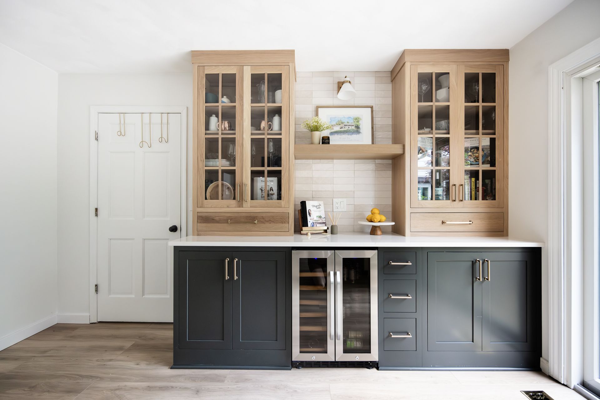 Kitchen bar with wooden upper cabinets, dark blue lower cabinets, and wine fridge.