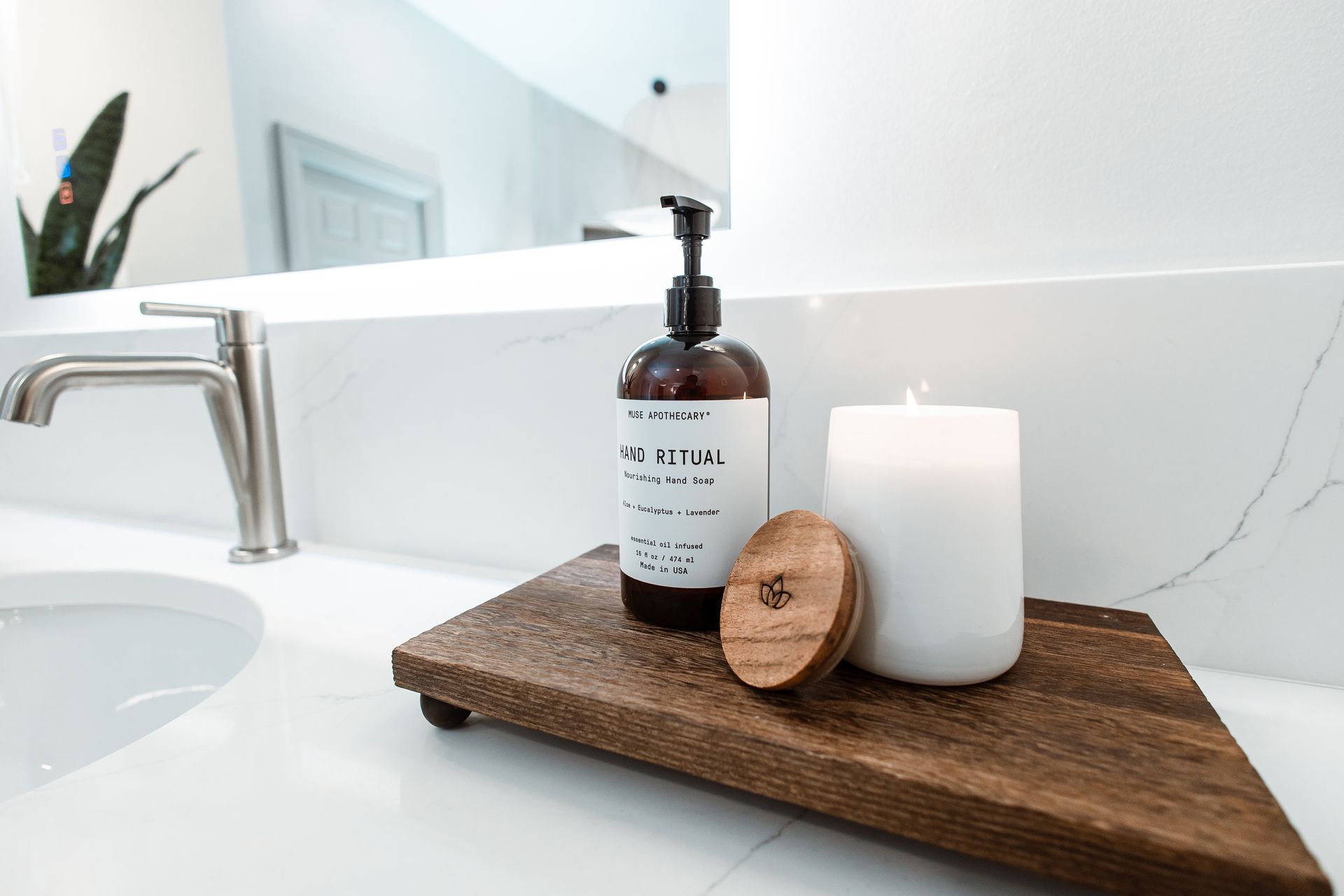 Bathroom counter with soap dispenser, wooden tray, candle, and soap.