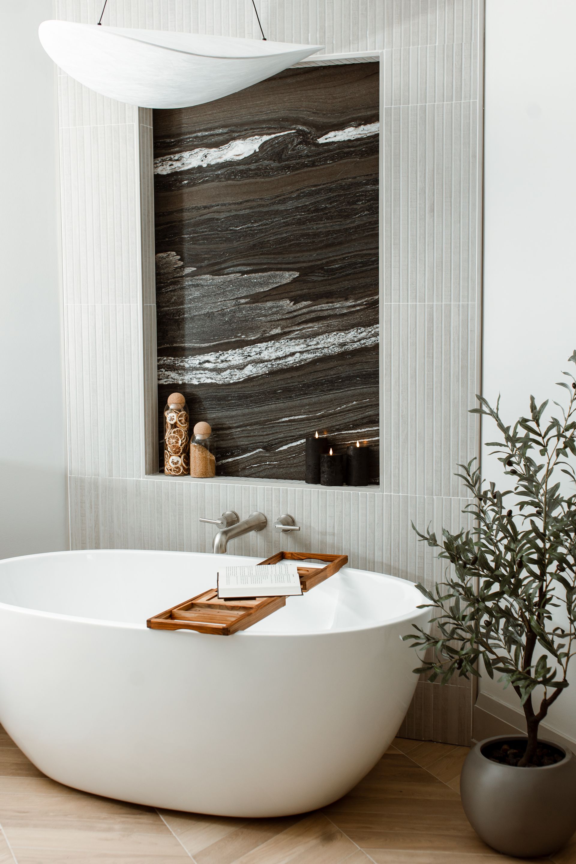 Elegant bathroom with white soaking tub, built-in shelf, and decorative plant.