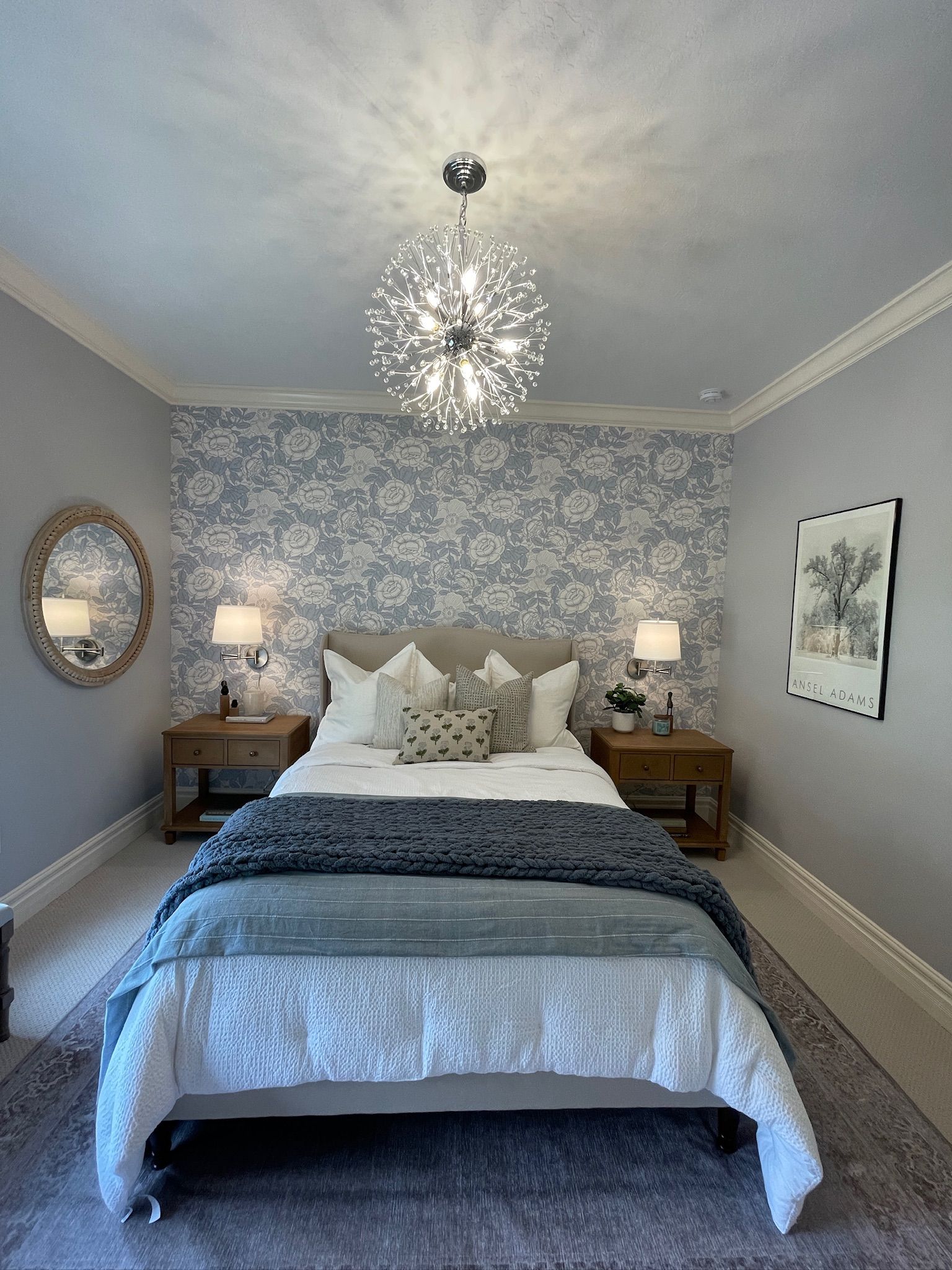 Bedroom with patterned wallpaper, bed, nightstands, lamps, and a decorative light fixture.