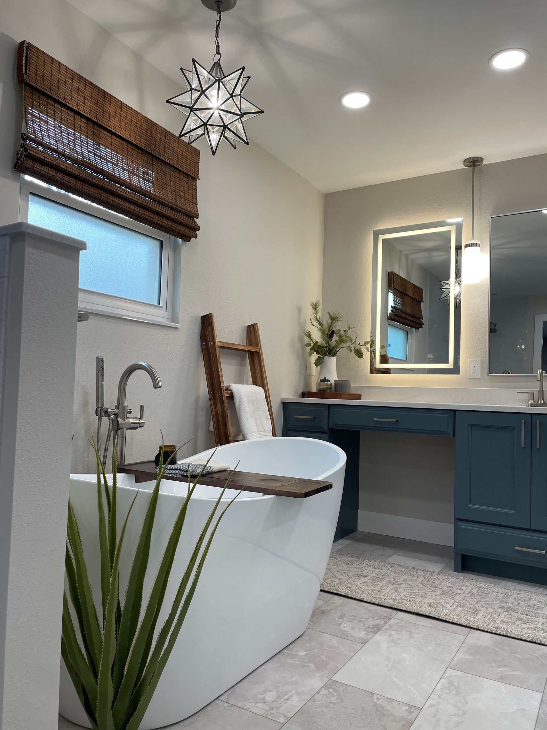 Modern bathroom with freestanding tub, blue vanity, and star-shaped light fixture.