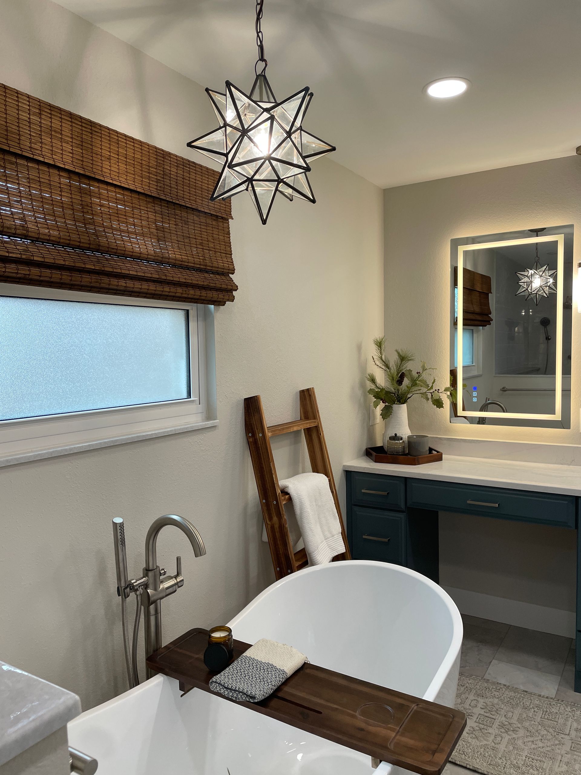 Bathroom with a white tub, wooden ladder, blue vanity, and a star-shaped light fixture.