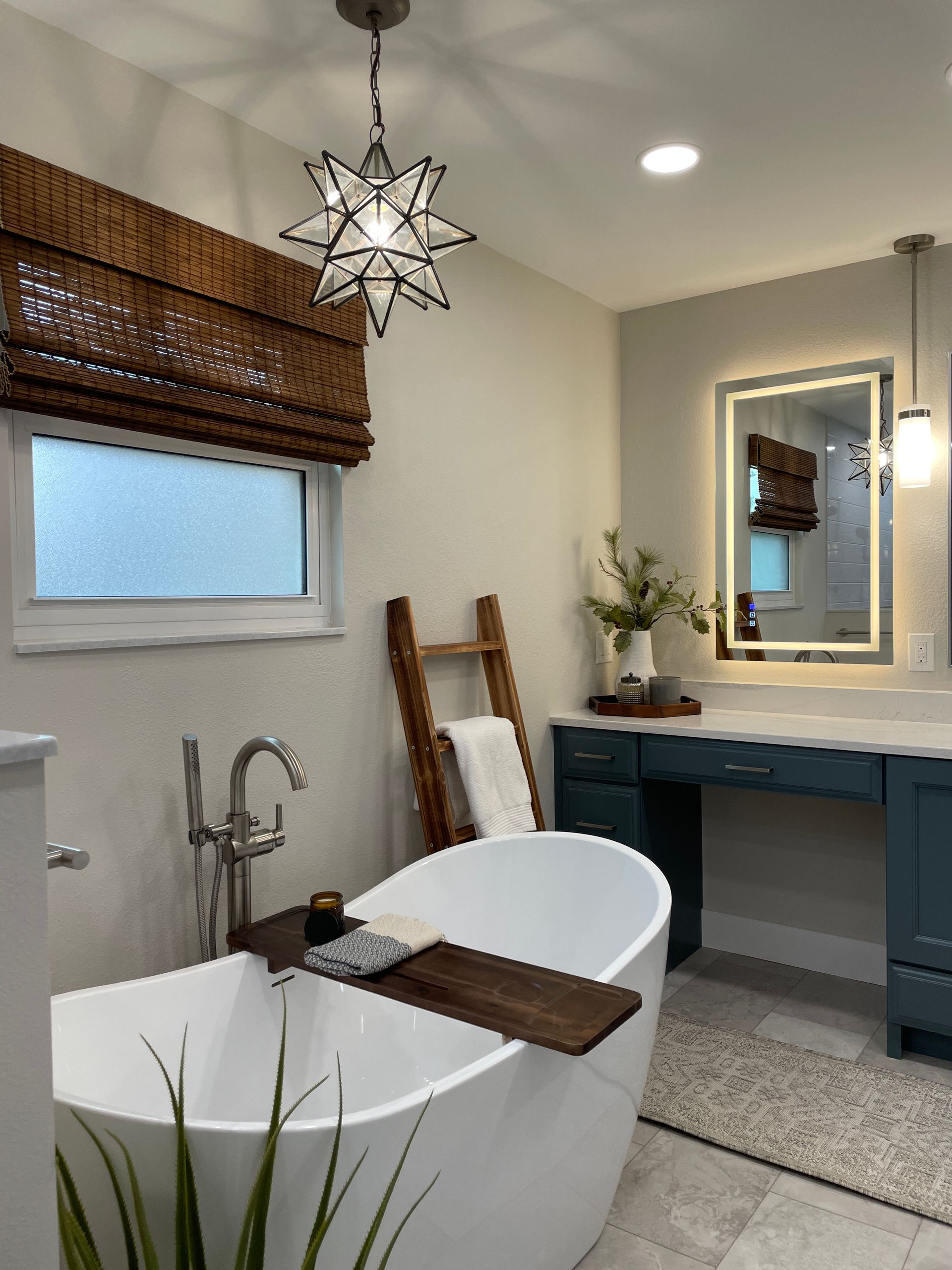 Bathroom with a white freestanding tub, star pendant light, and a blue vanity.