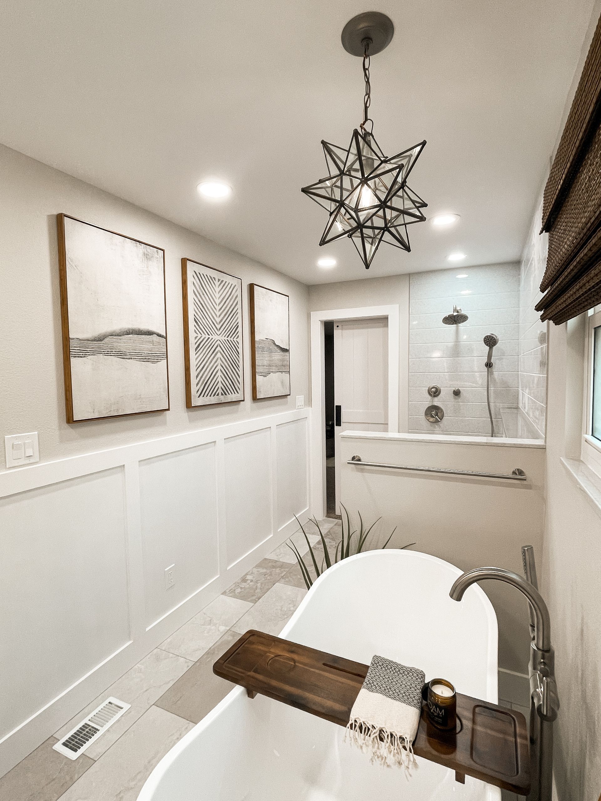 Bathroom with a freestanding tub, star-shaped light fixture, and three framed art pieces on the wall.