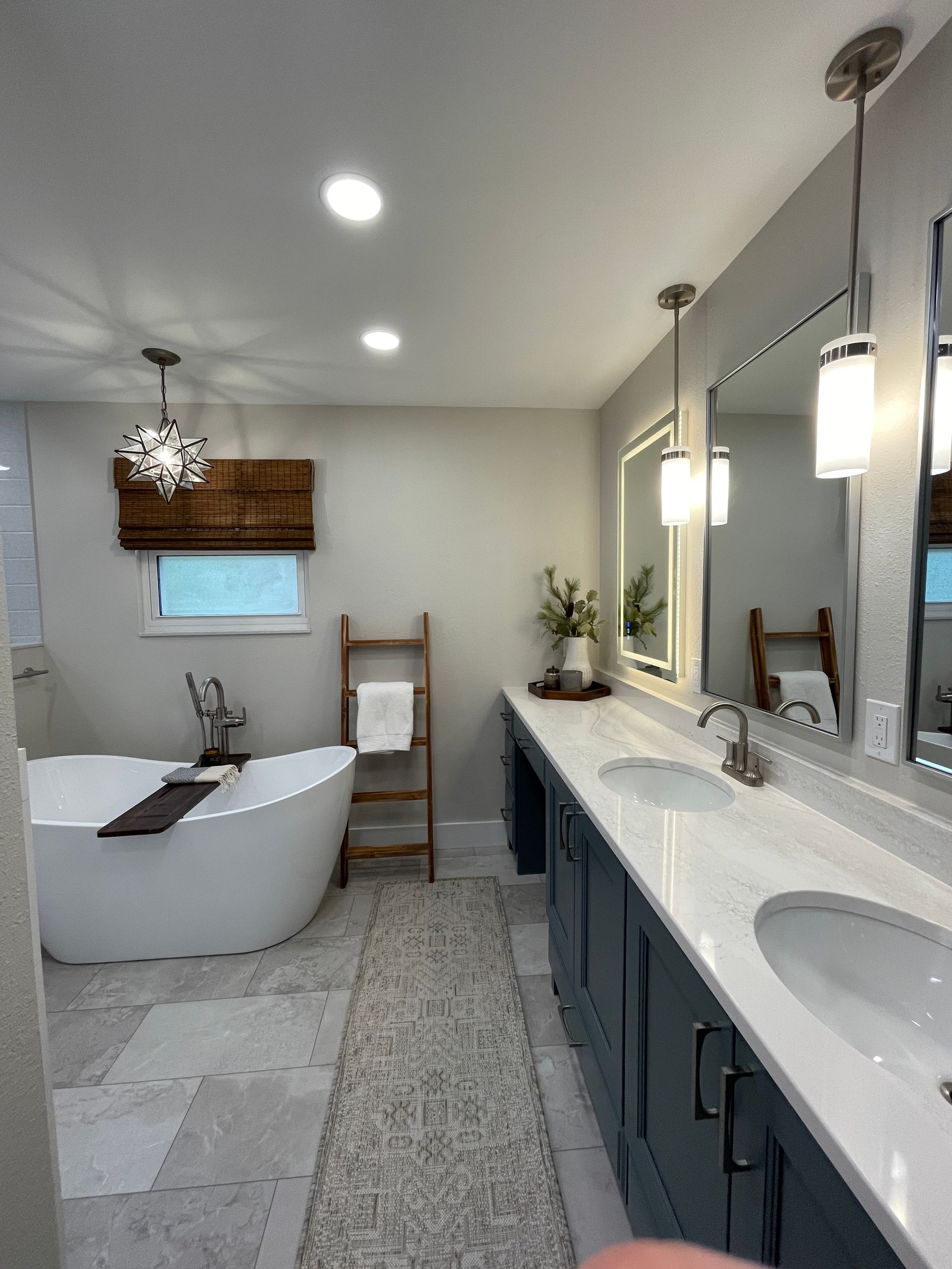 Bathroom with a white soaking tub, vanity with two sinks, and decorative wood ladder.