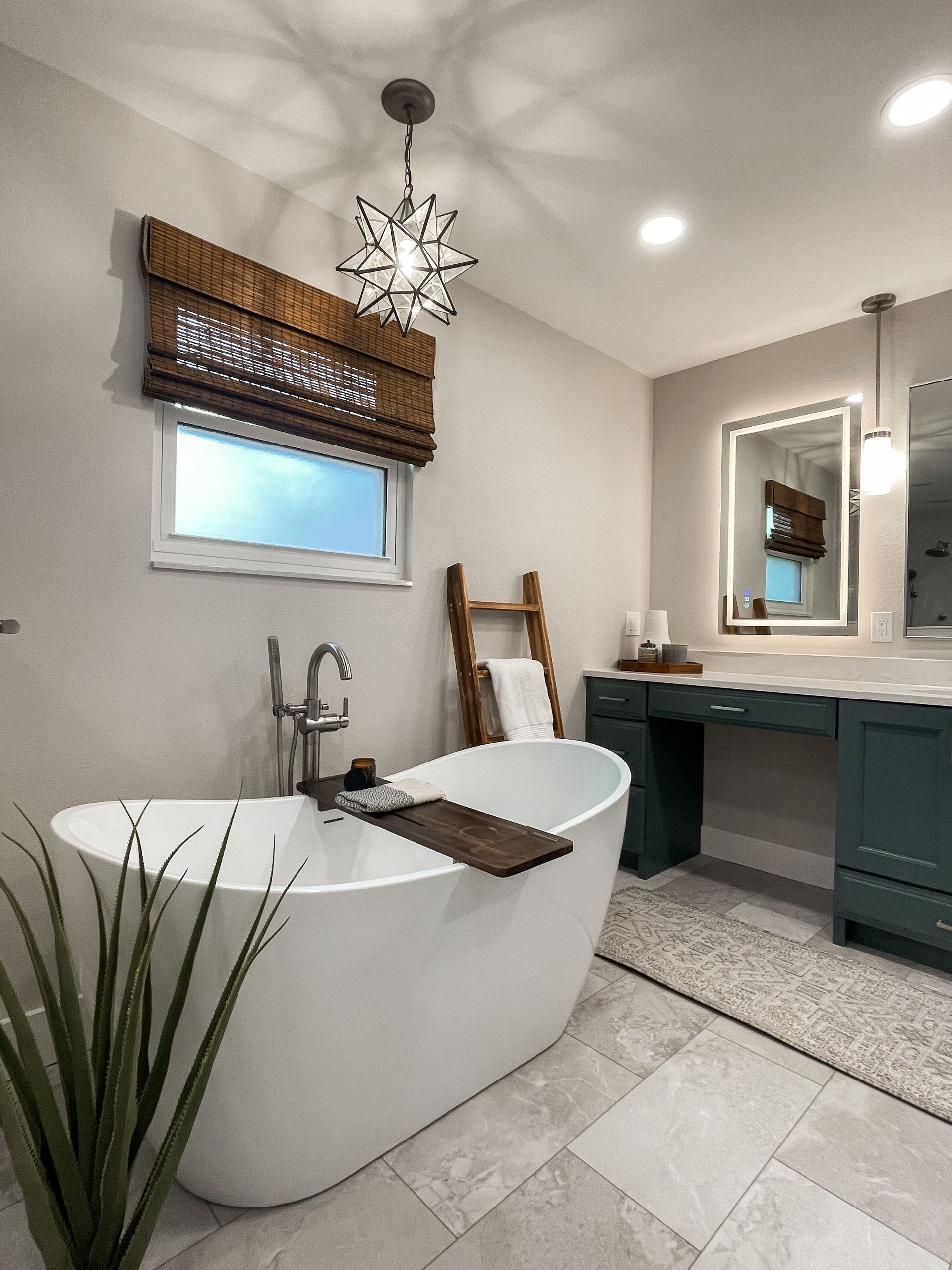 Bathroom with white soaking tub, teal vanity, and starburst light fixture.