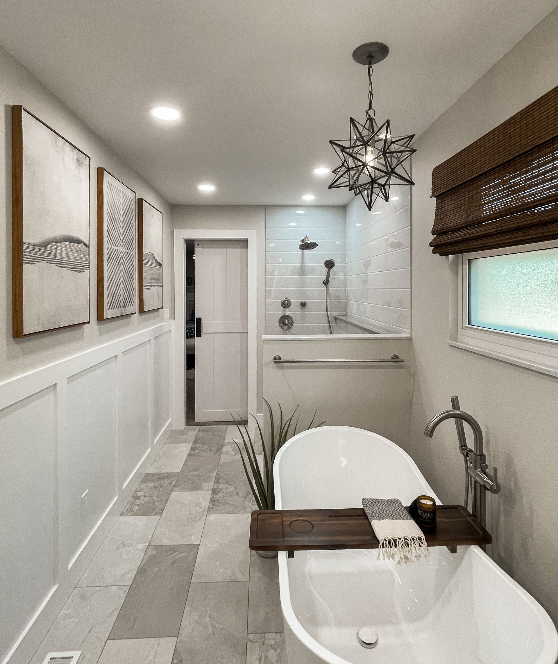 Narrow bathroom with white walls, a standalone tub, shower, and decorative lighting.