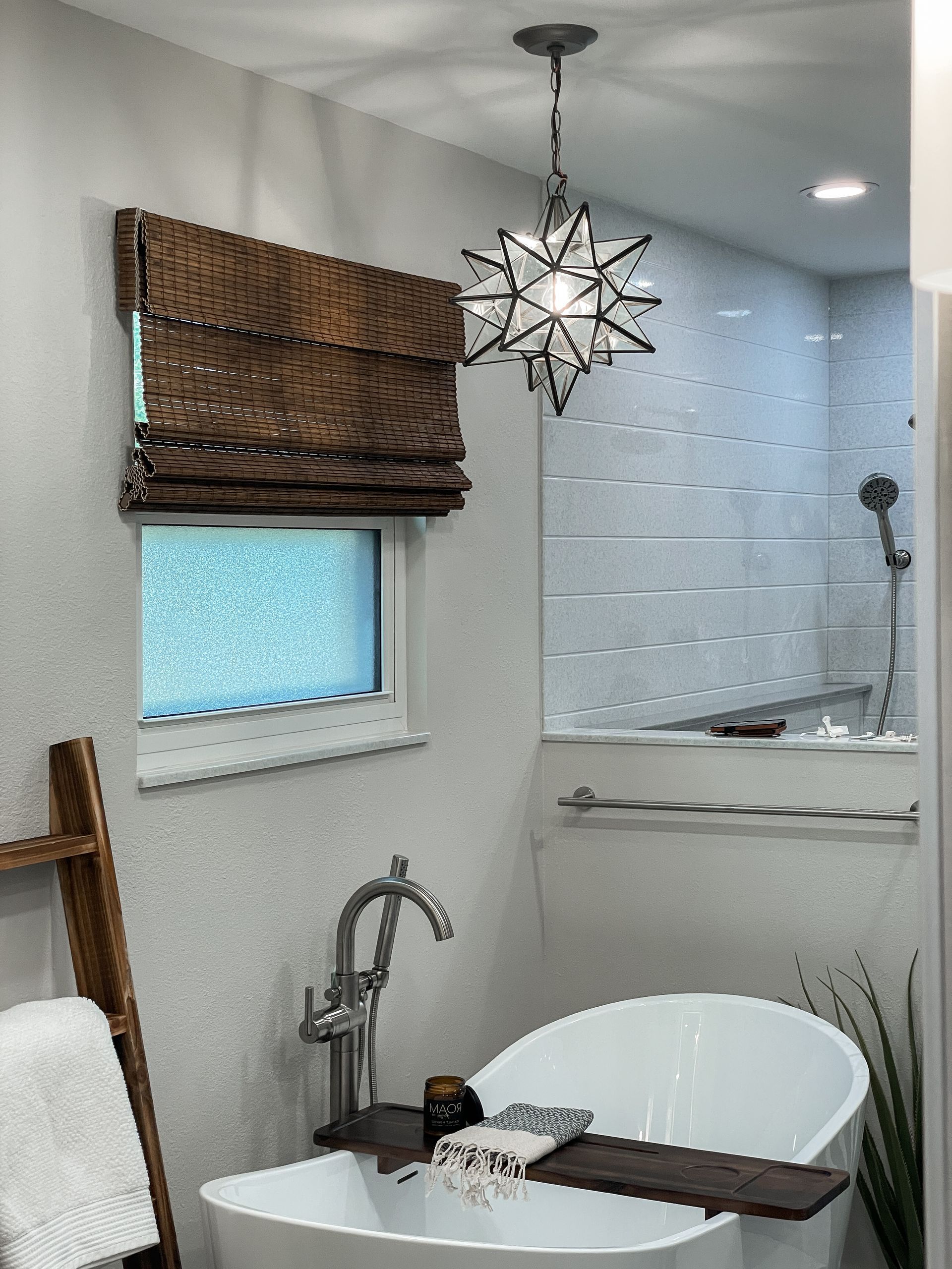 Bathroom with a star-shaped pendant light, a wicker window shade, and a free-standing tub.
