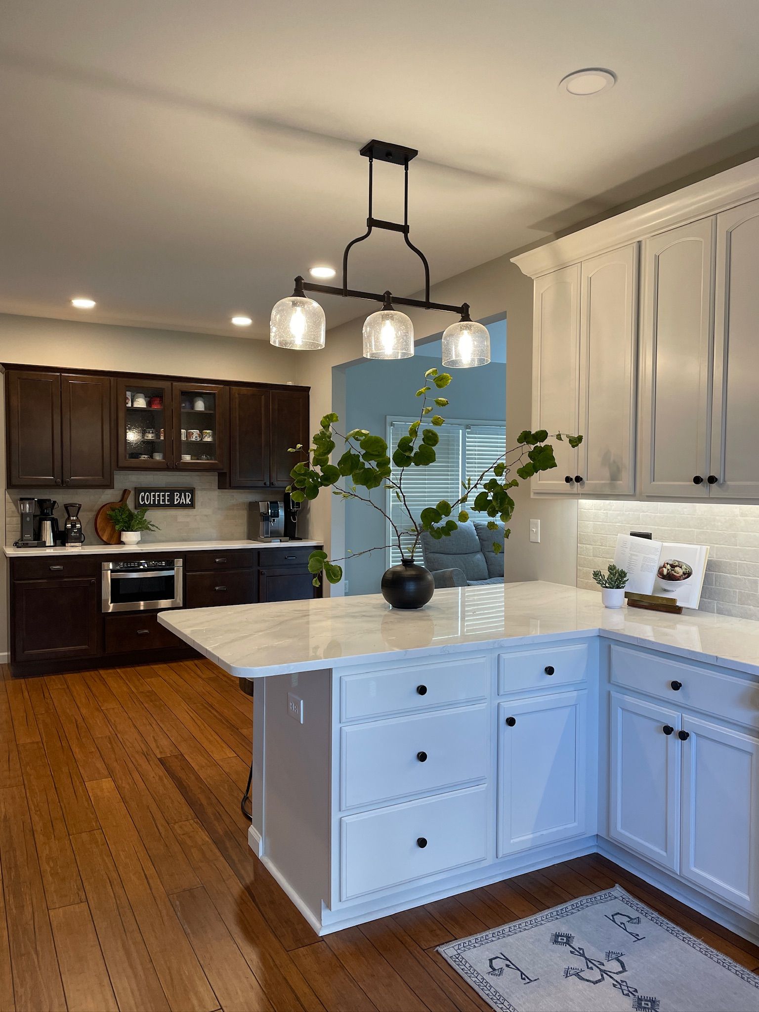 Kitchen with white cabinets, dark wood island, and dark wood cabinets on back wall.