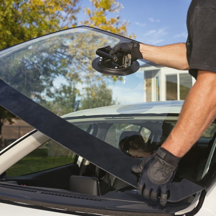 A man is installing a windshield on a car
