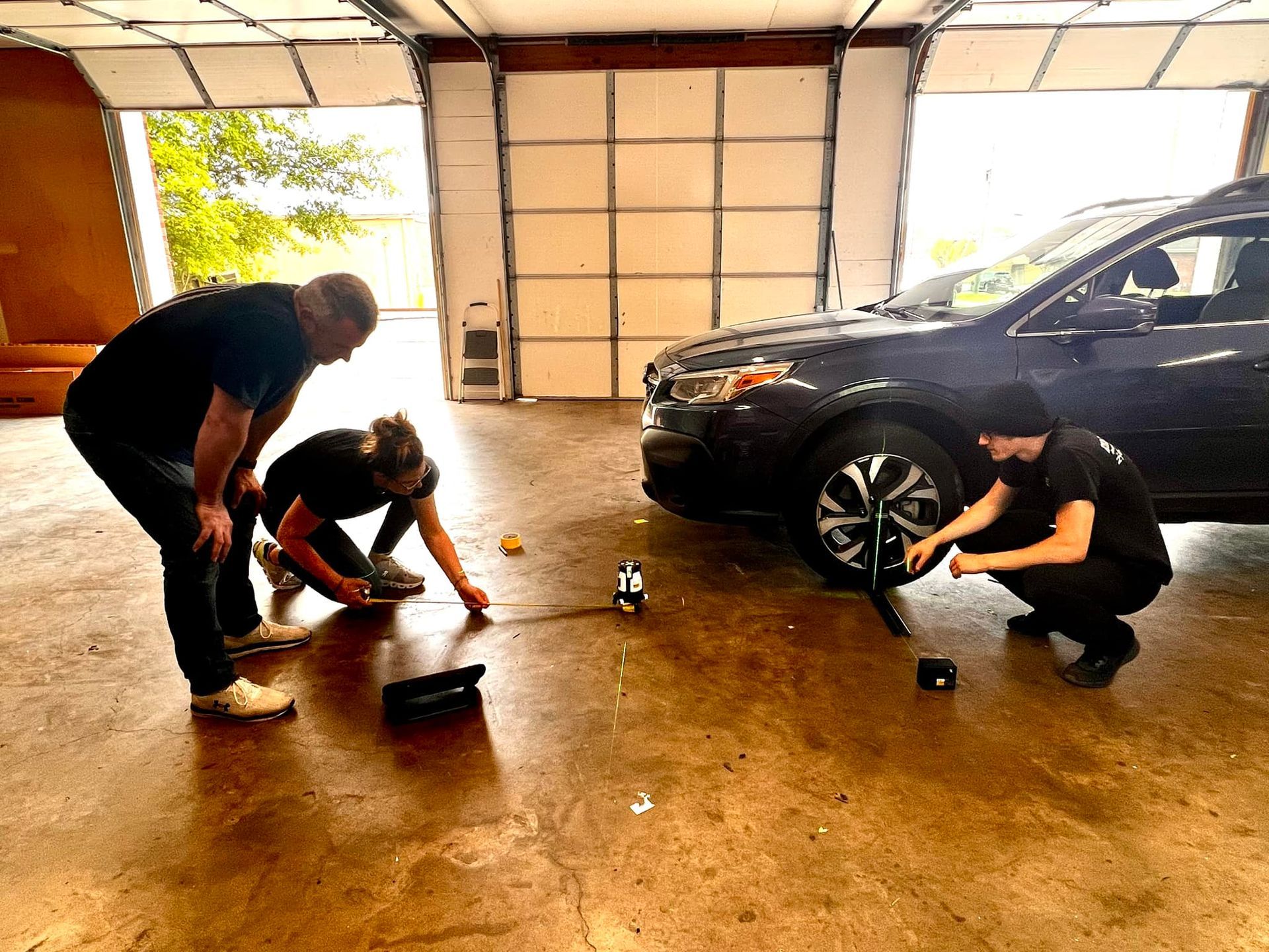 A group of people are working on a car in a garage.