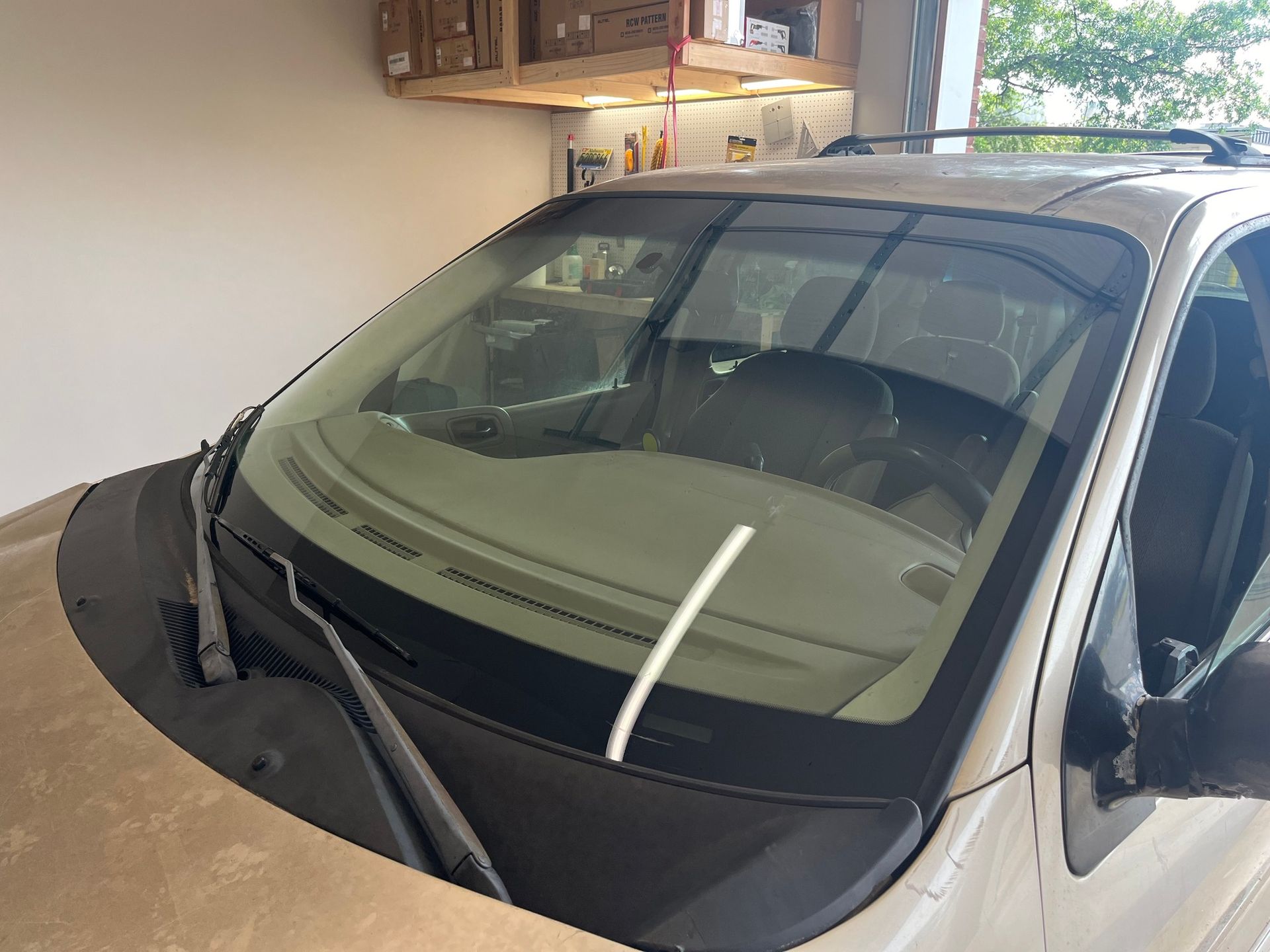 A white car is parked in a garage with its windshield wiper missing.