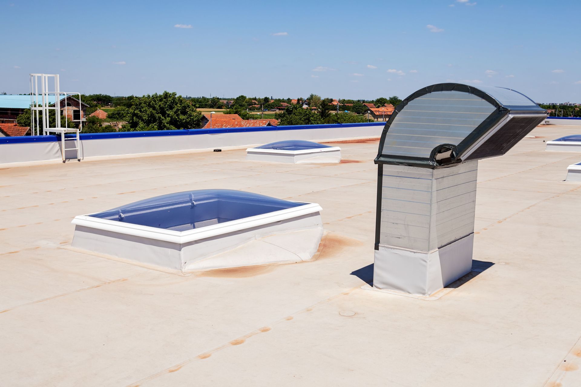 Flat rooftop with skylights and an open vent. Sunny day, clear sky.