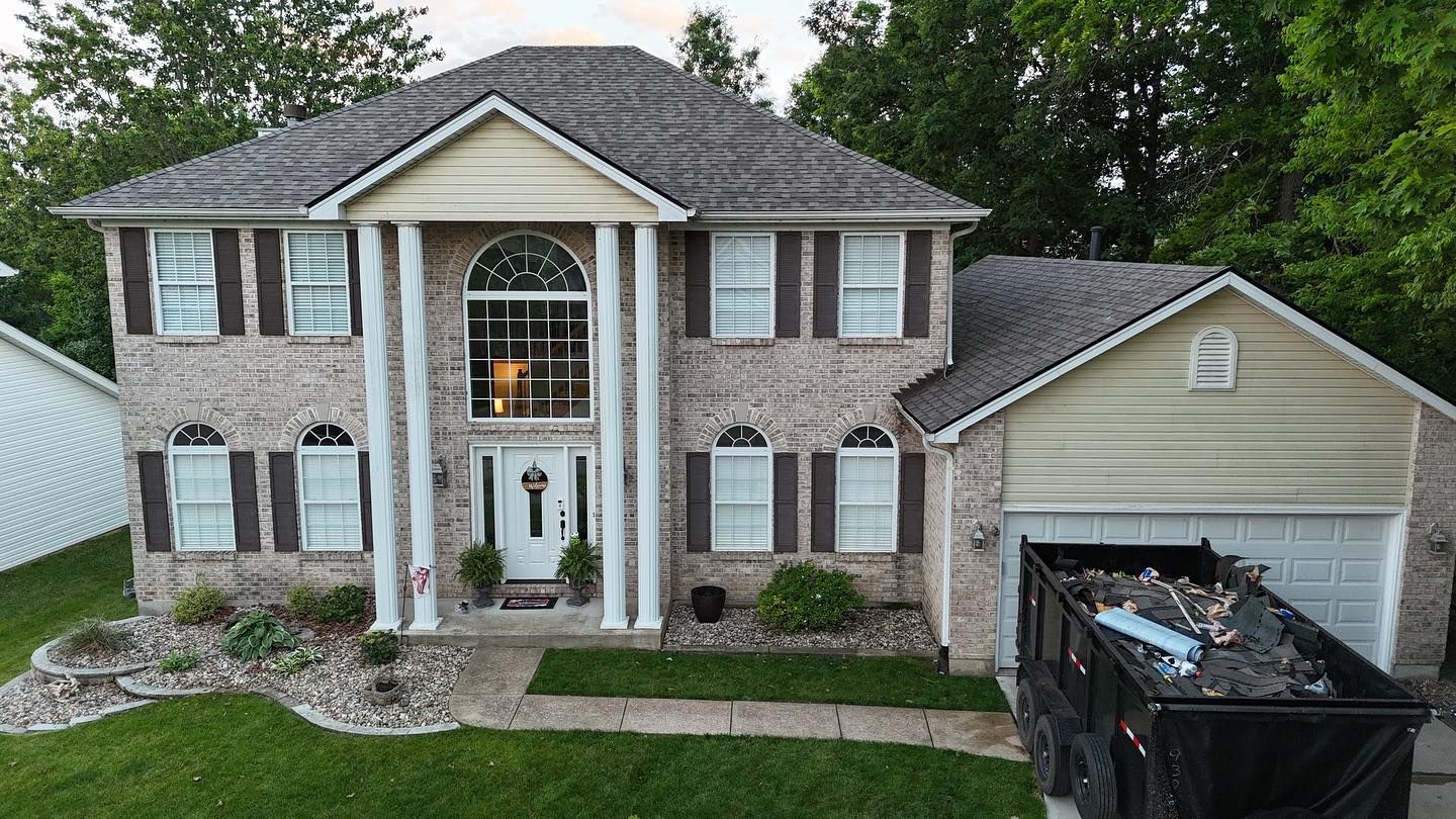 Two-story house with columns, brown shutters, a dumpster in front of the garage; roof repair.