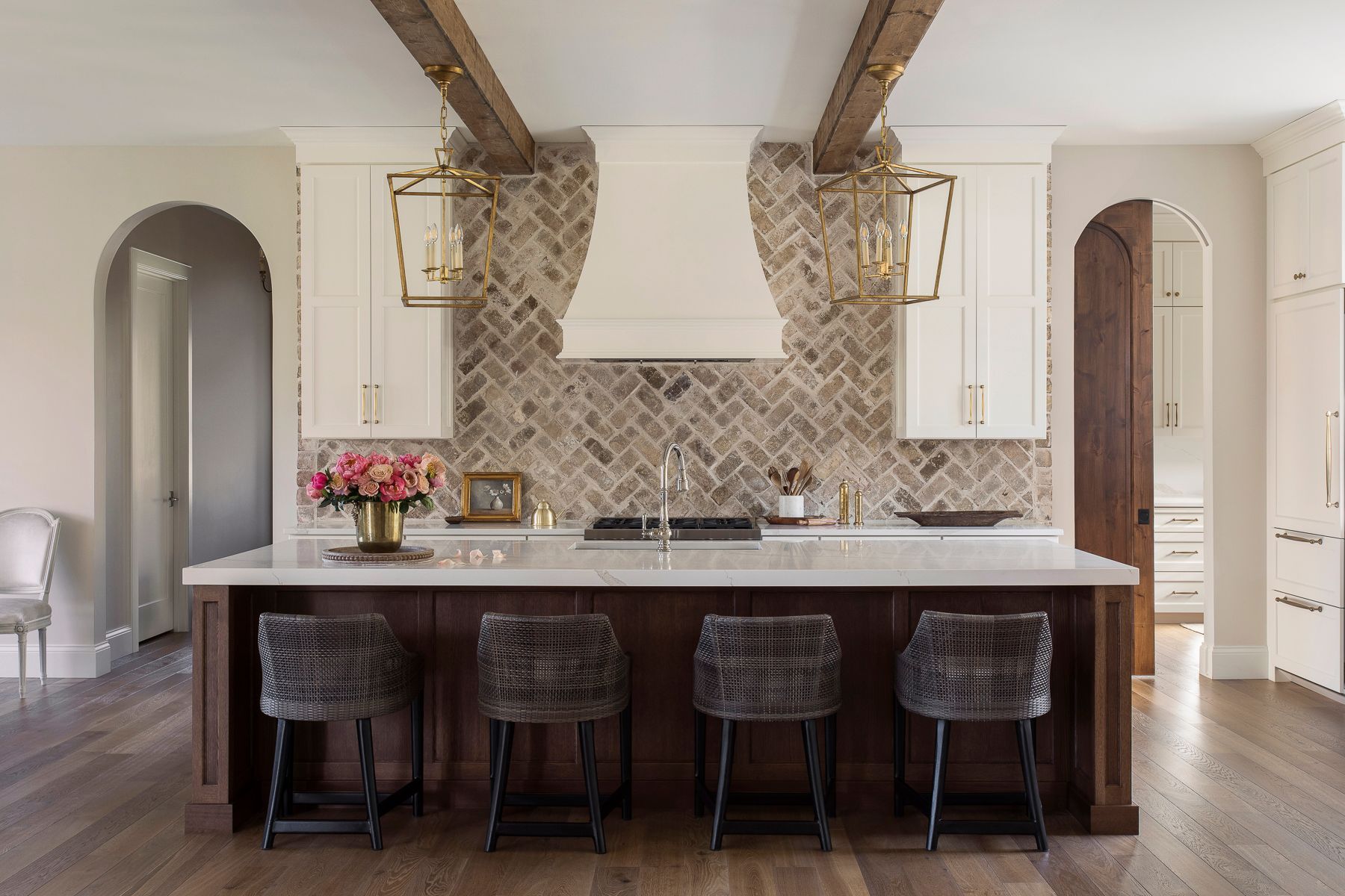 A kitchen with a large island, stools, and a stove.
