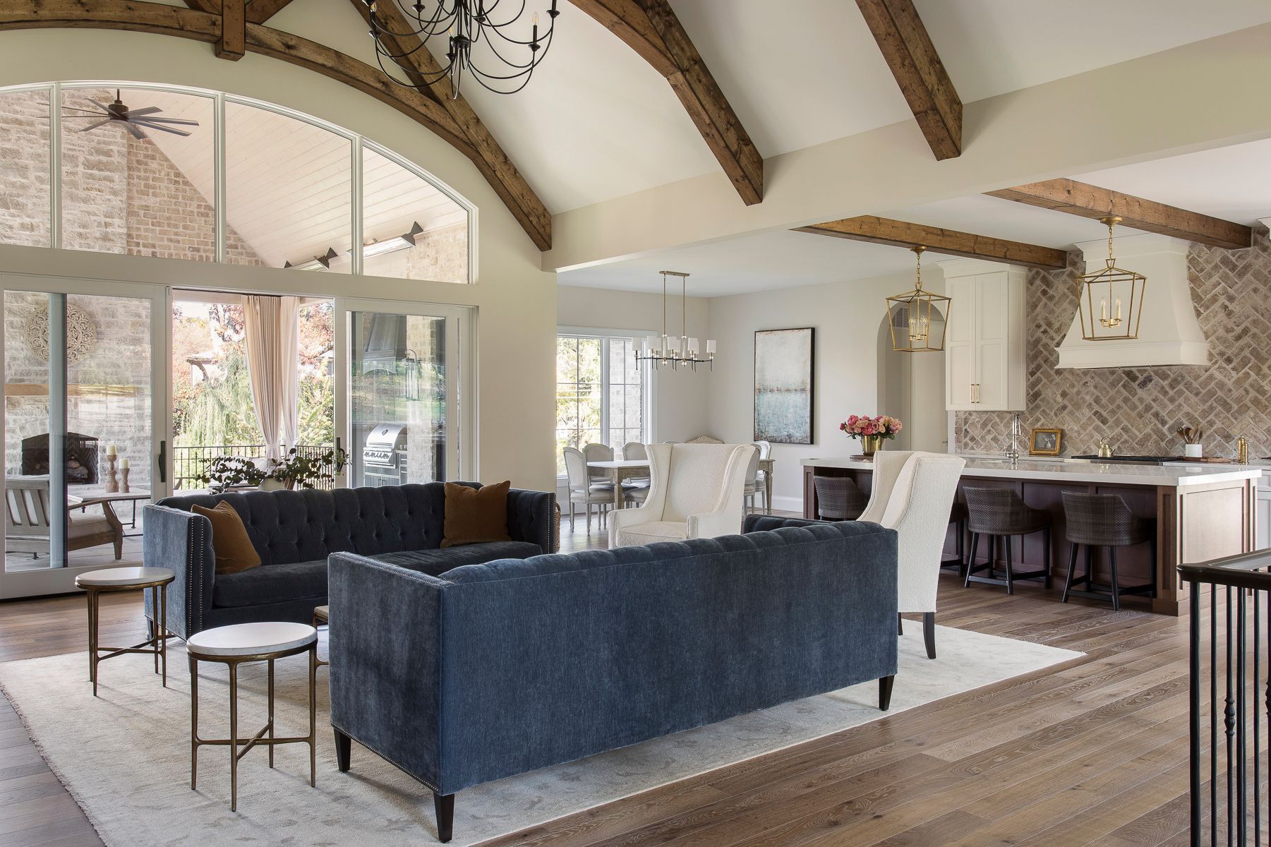 A living room with a blue couch, chairs, tables, and a kitchen.