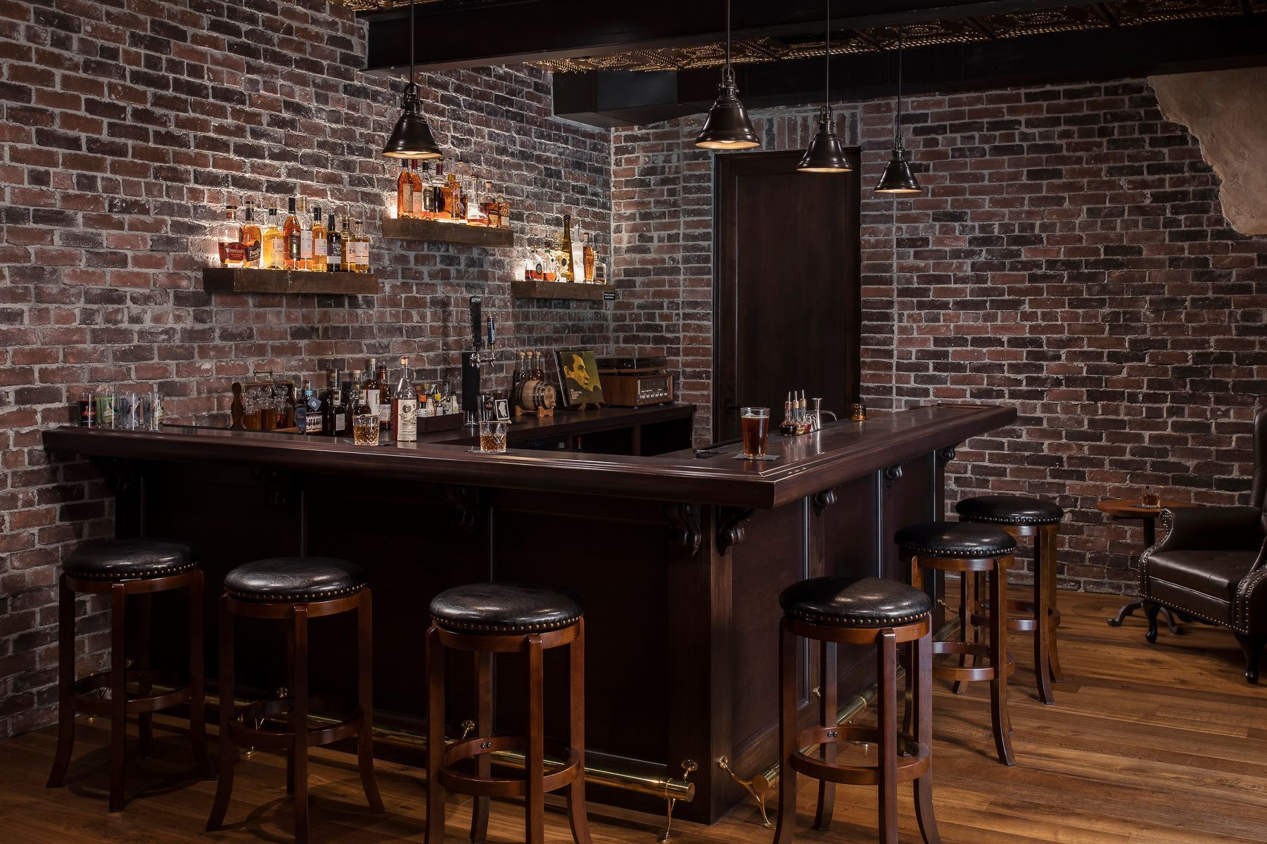 A bar with stools and a brick wall.