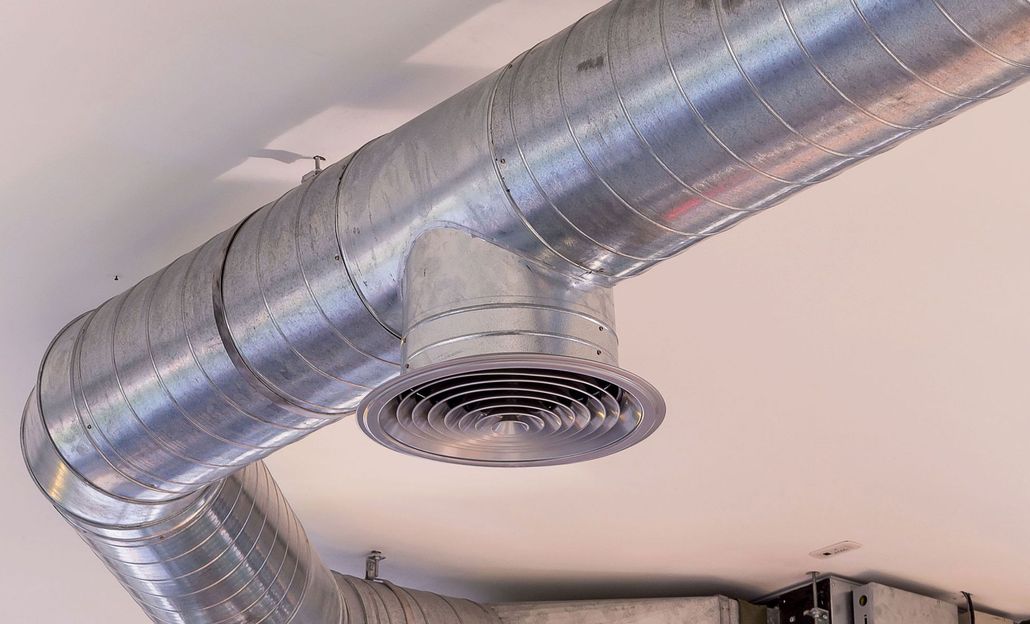 Galvanized metal HVAC ductwork with a circular vent, mounted on a white ceiling.