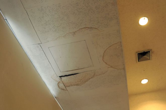 Ceiling with a square access panel, vents, and recessed lights in a beige room