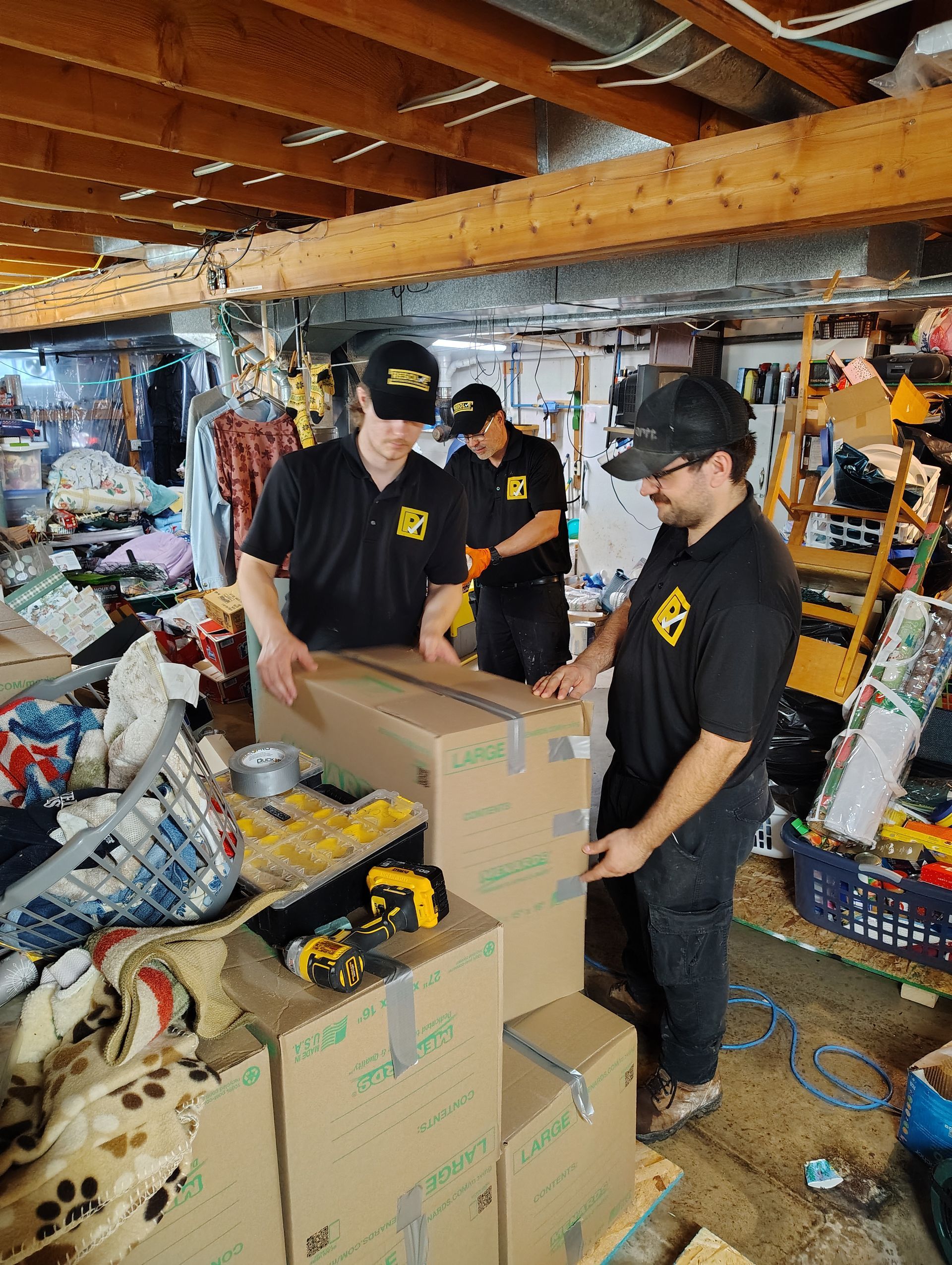 Volunteers in black shirts sort and pack boxes in a cluttered storage room