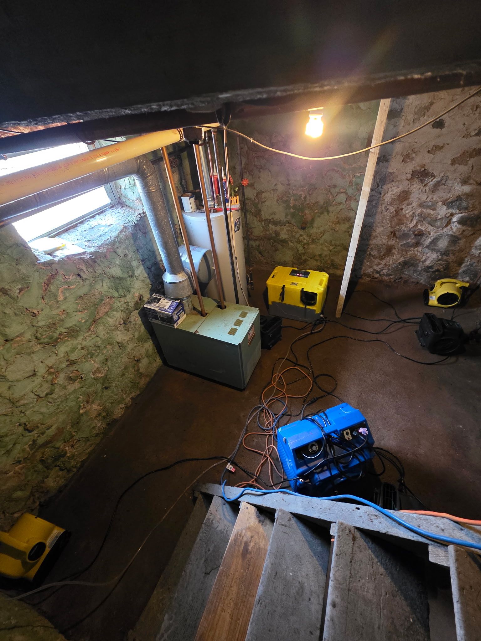 High-angle view of an indoor workspace with scattered tools, cables, and bright yellow and blue equipment.