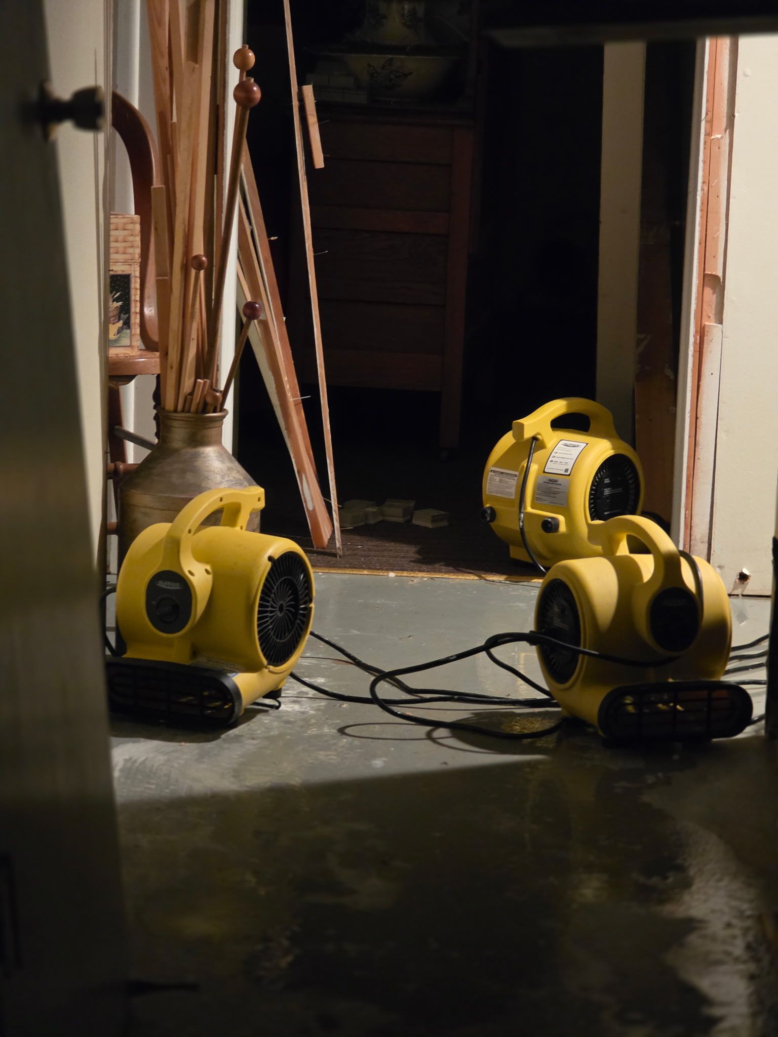 Three yellow air movers on a dim hallway floor with cords trailing across it