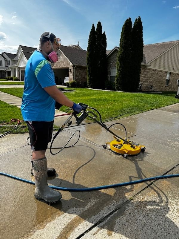 A man is cleaning a driveway with a pressure washer.