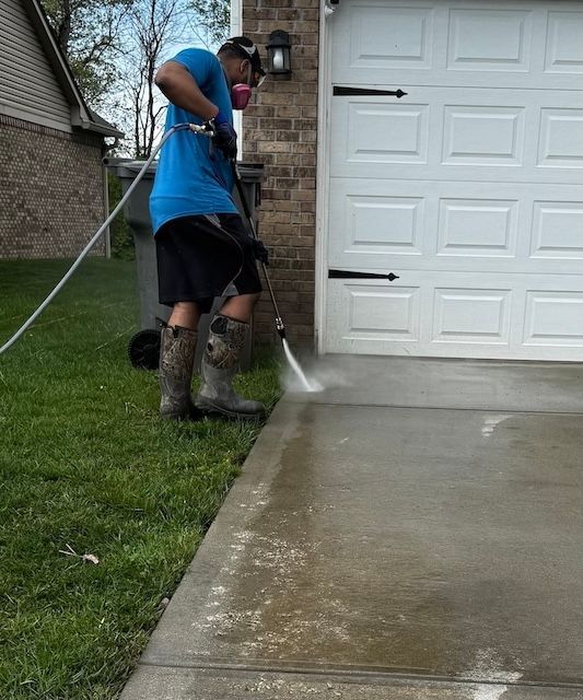 A man is using a high pressure washer to clean a driveway